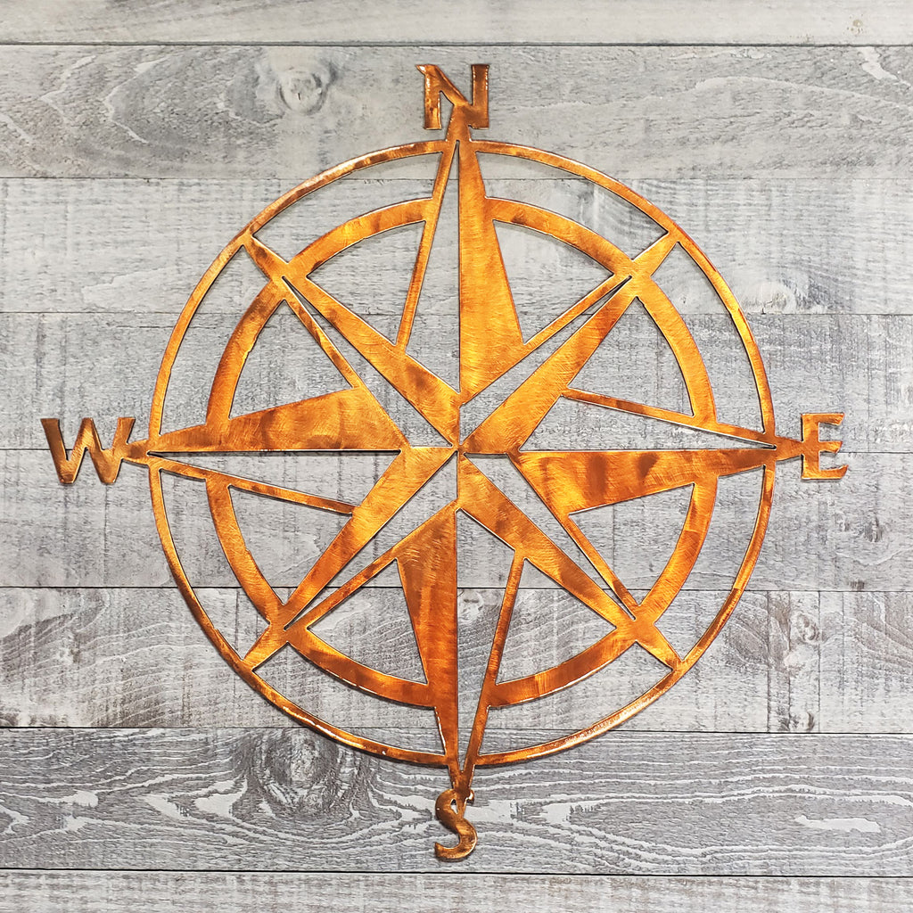 Copper colored compass wall decor on a wooden background