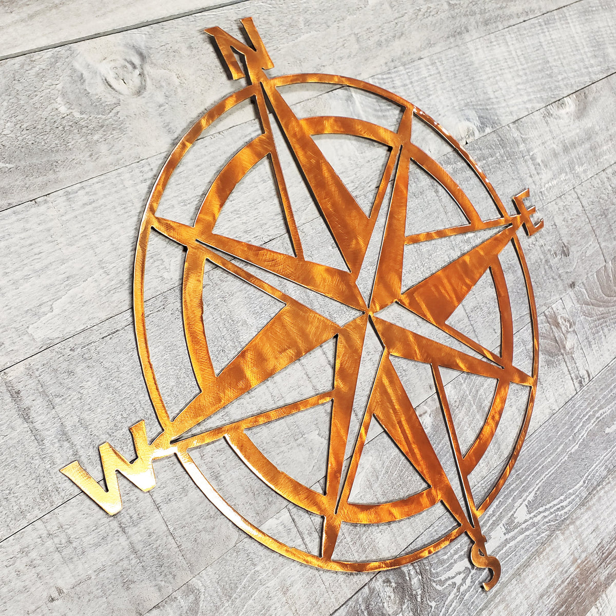 Copper colored compass rose on a wooden surface