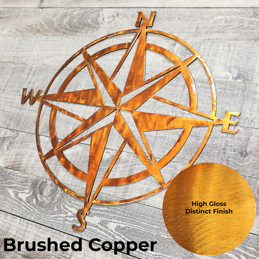 Metal compass wall art with 'Brushed Copper' finish on a wooden surface
