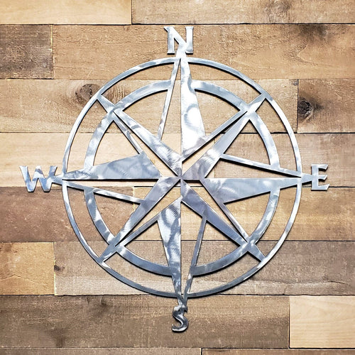 Metal compass wall art on a wooden background