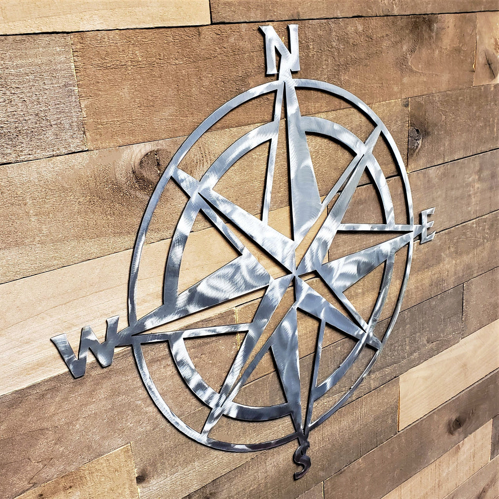 Metal compass wall art on a wooden background