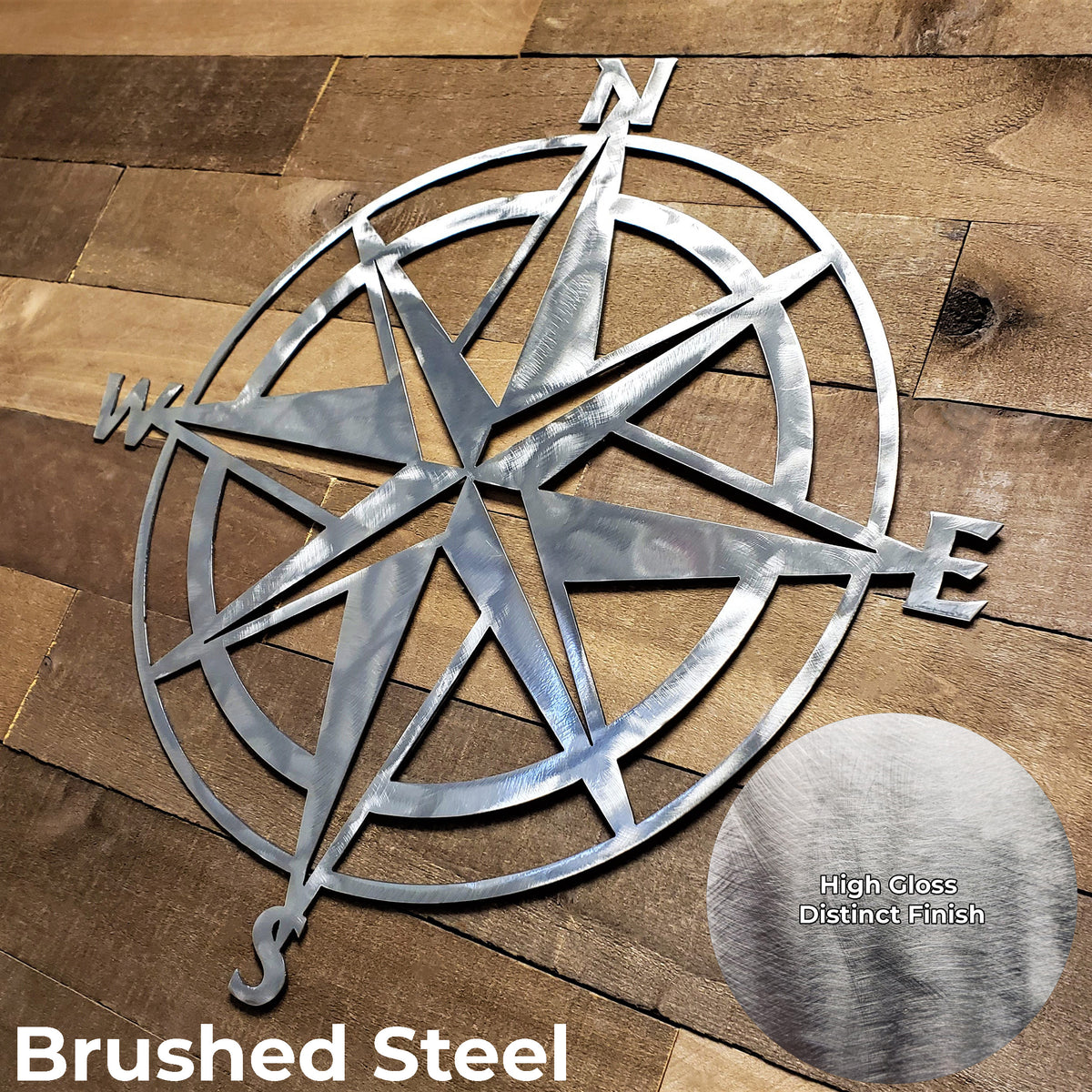 Metal compass wall art on a wooden surface with 'Brushed Steel' text.