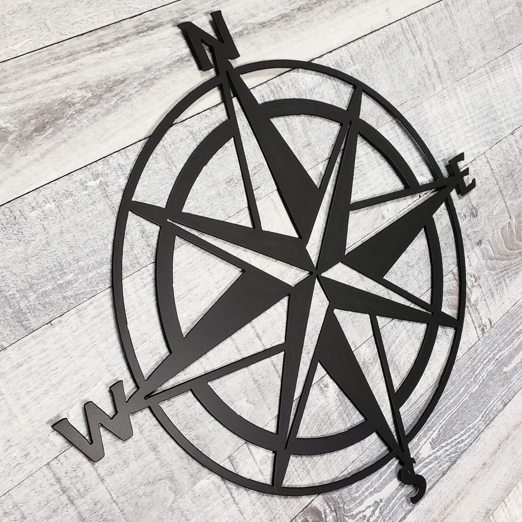 Black compass wall decor on a wooden surface