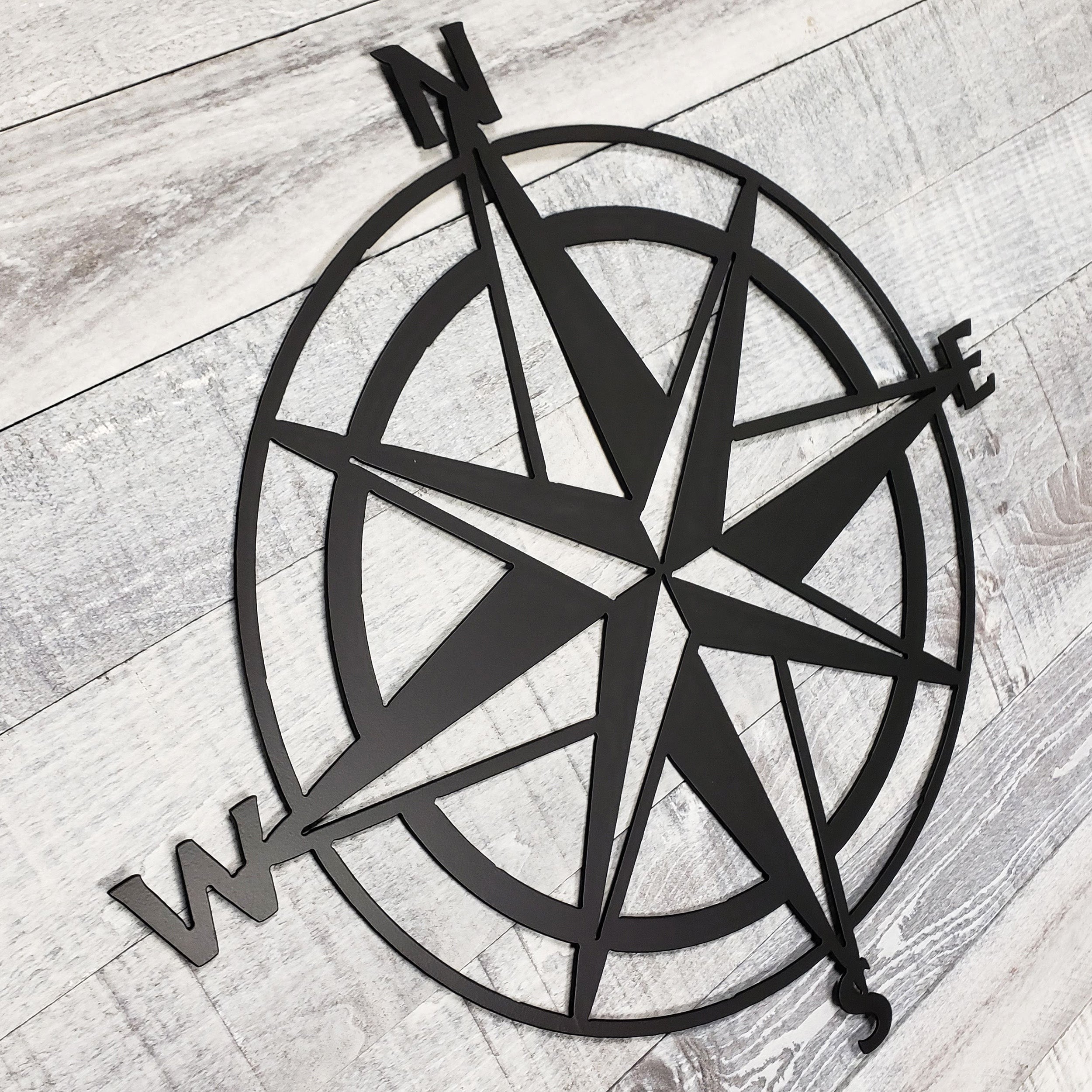 Black compass wall decor on a wooden surface