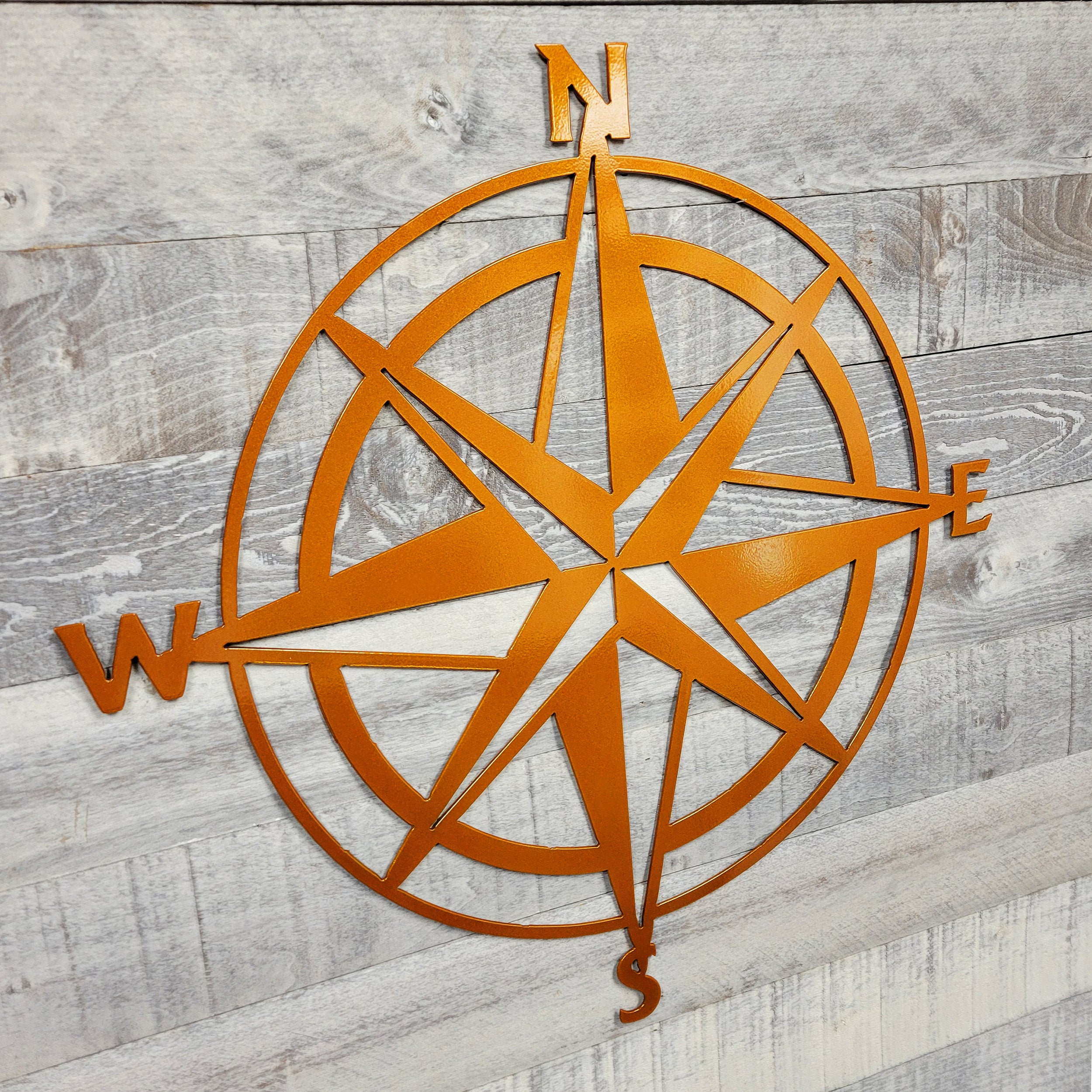 Metal compass wall art on a wooden background