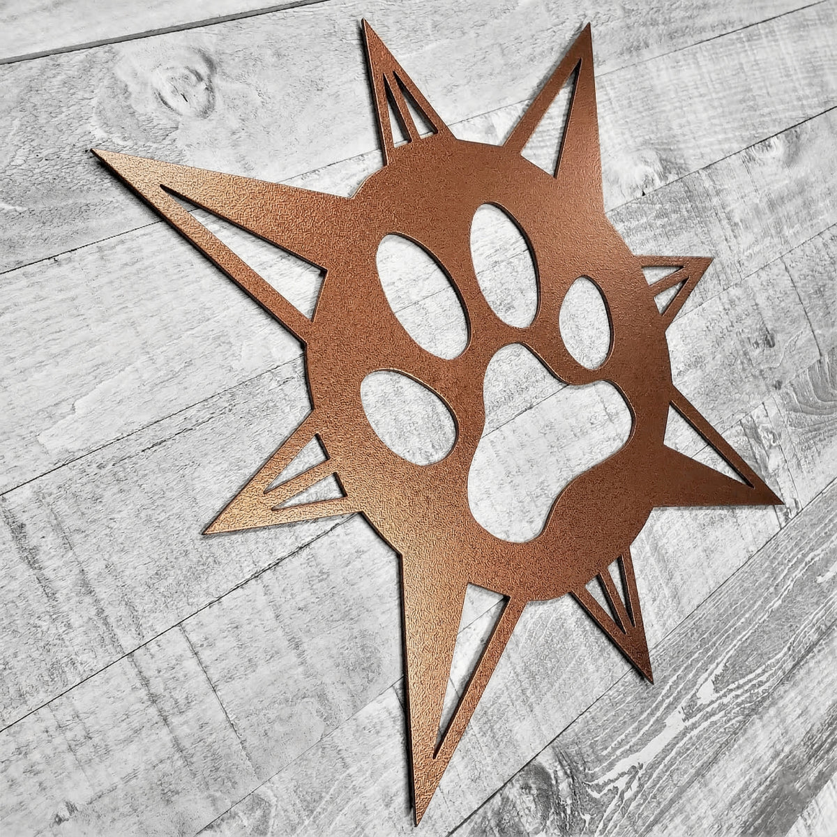 copper-colored compass rose with dog paw in center on a wooden background