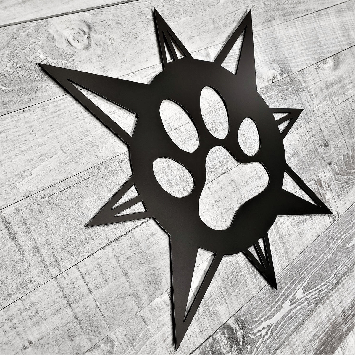 black compass rose with dog paw in center on a wooden background