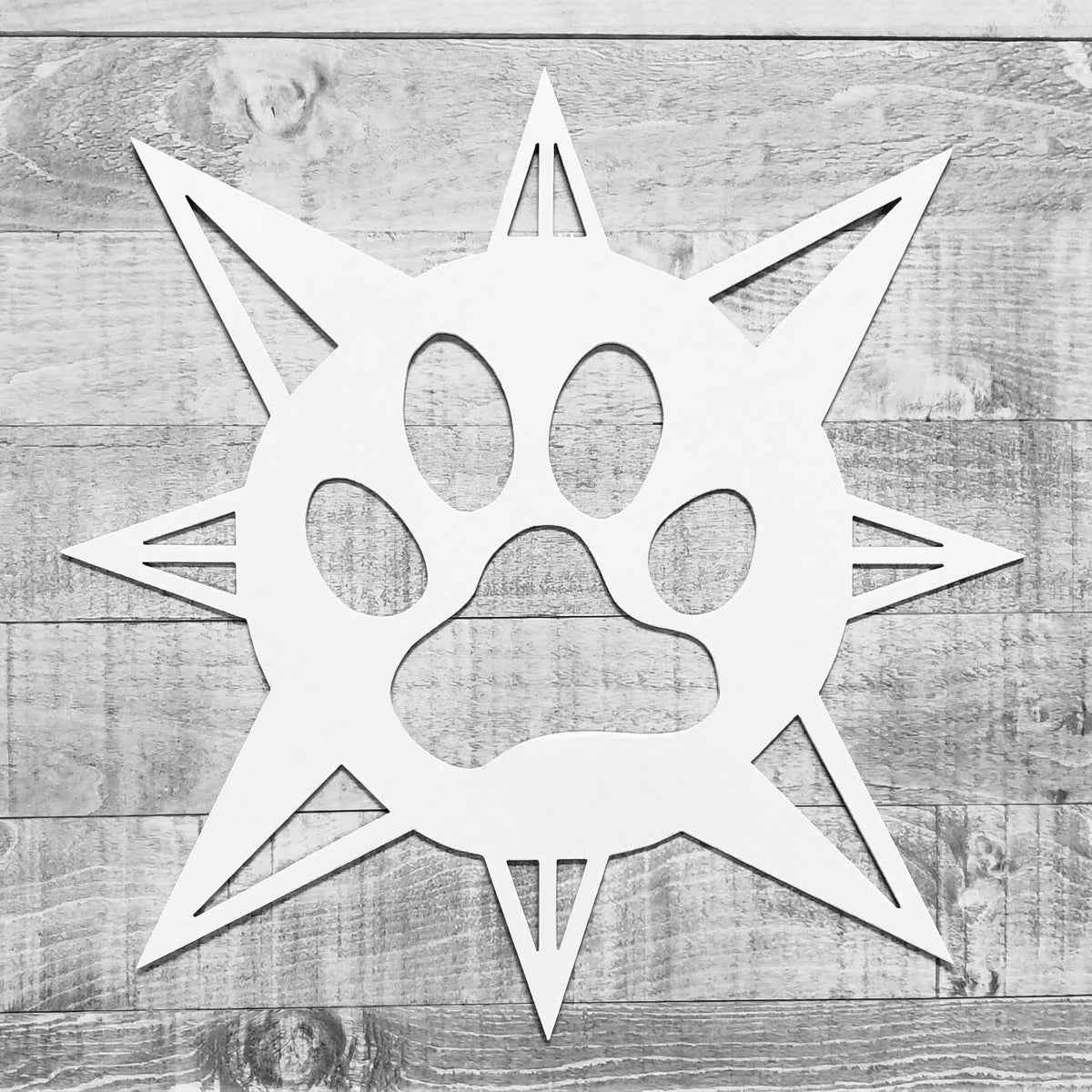 white compass rose with dog paw in center on a wooden background