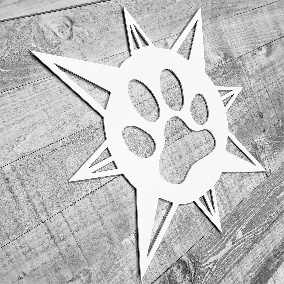 white compass rose with dog paw in center on a wooden background