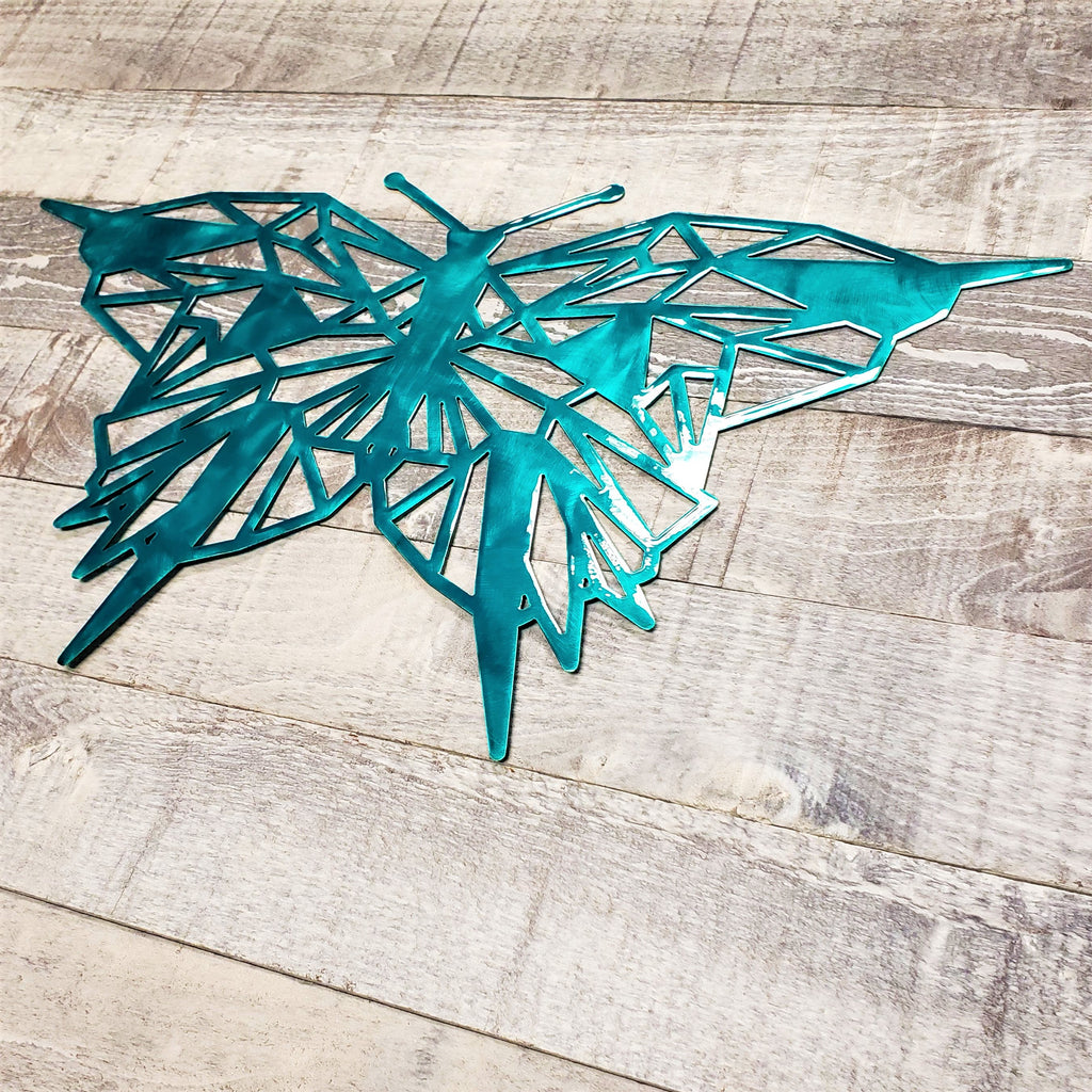 geometric representation of a butterfly with a brushed aqua color finish on a wooden background