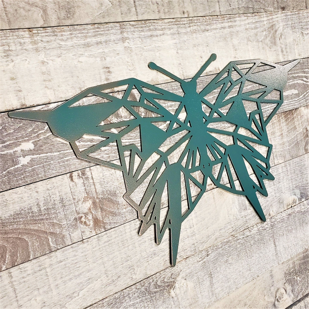 geometric representation of a butterfly with a copper and teal color finish on a wooden background