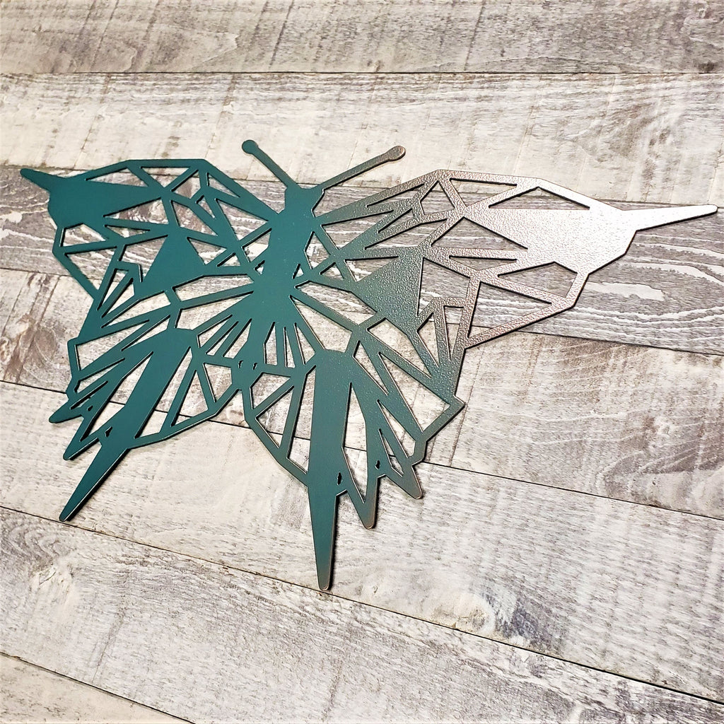 geometric representation of a butterfly with a copper and teal color finish on a wooden background