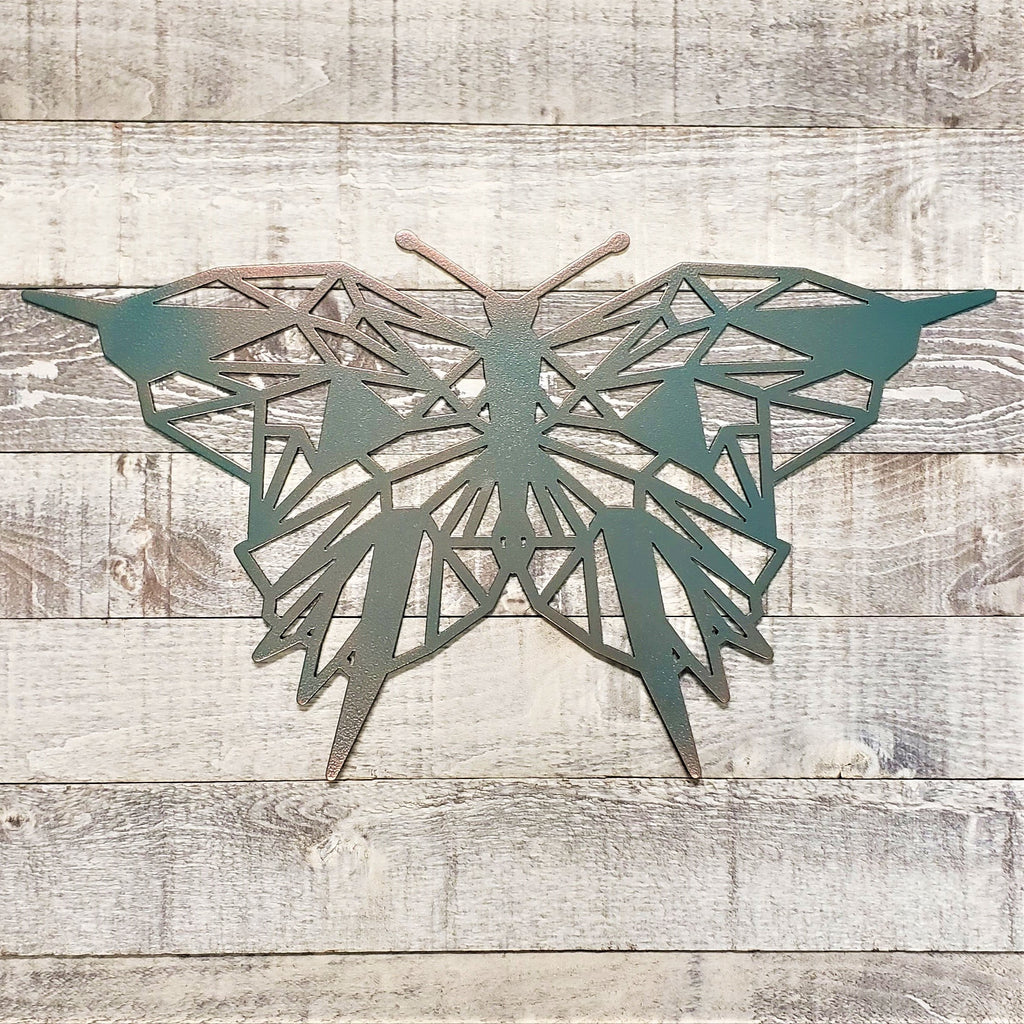 geometric representation of a butterfly with a copper and teal color finish on a wooden background