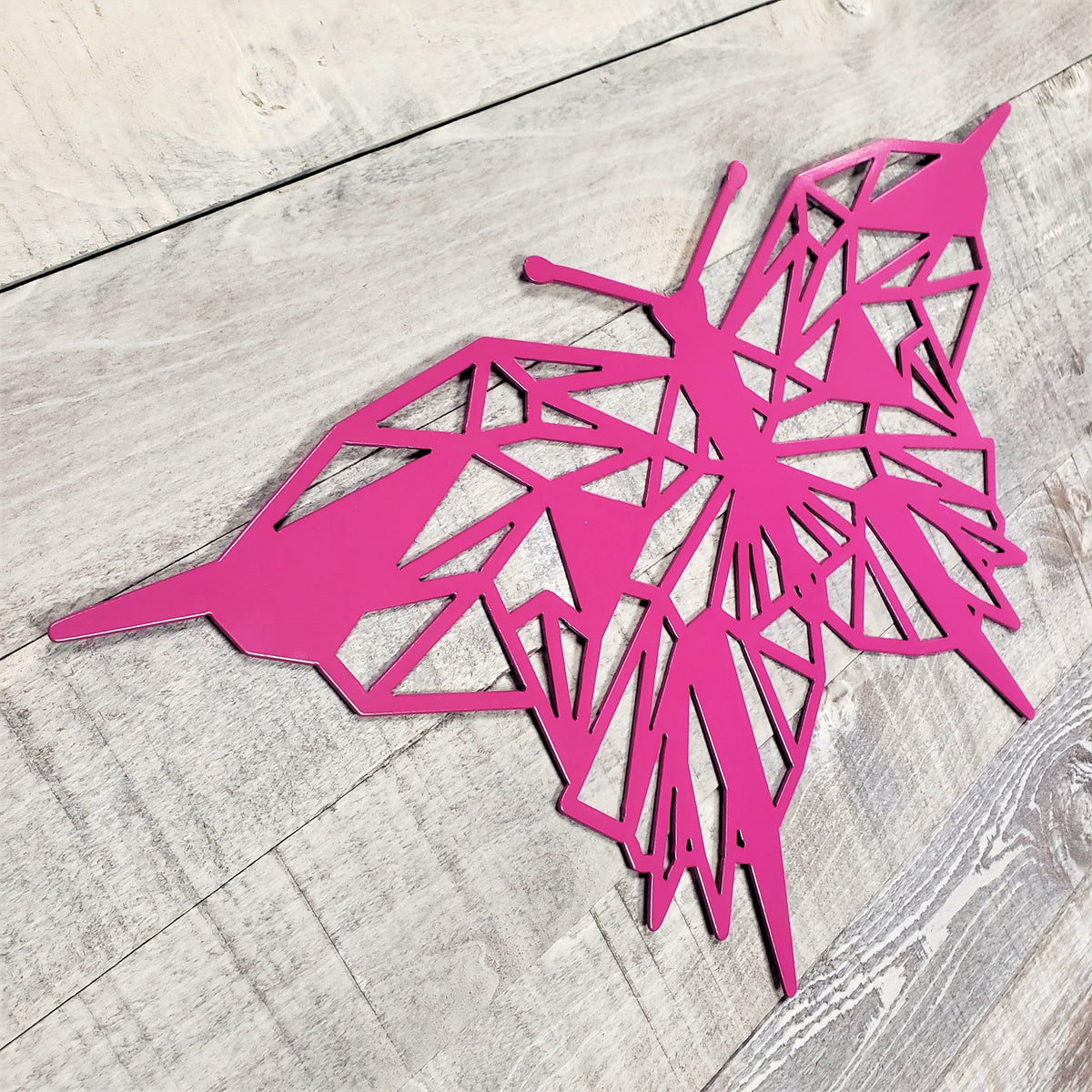 geometric representation of a butterfly with an electric purple color finish on a wooden background