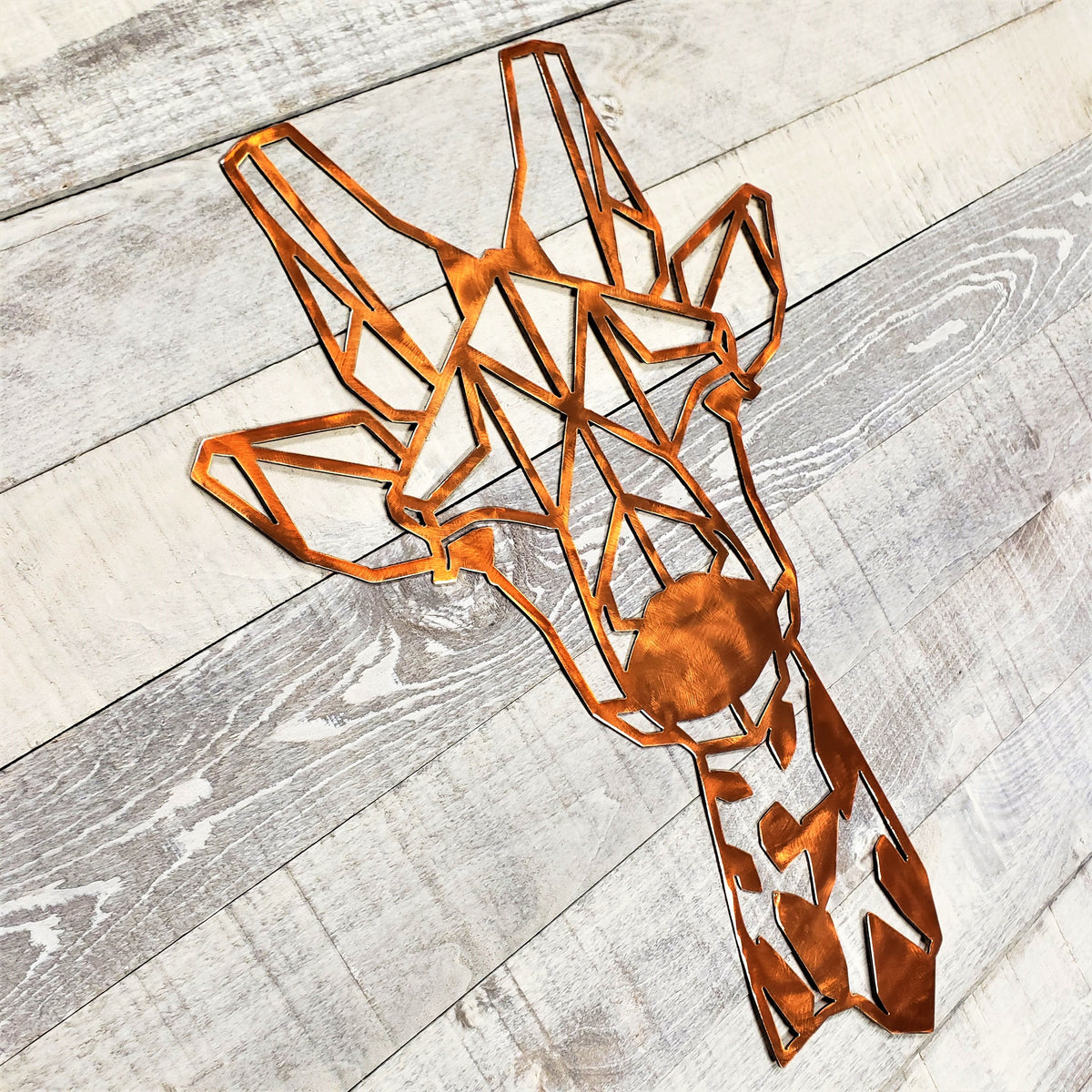 Copper-colored metal giraffe wall art on a wooden surface