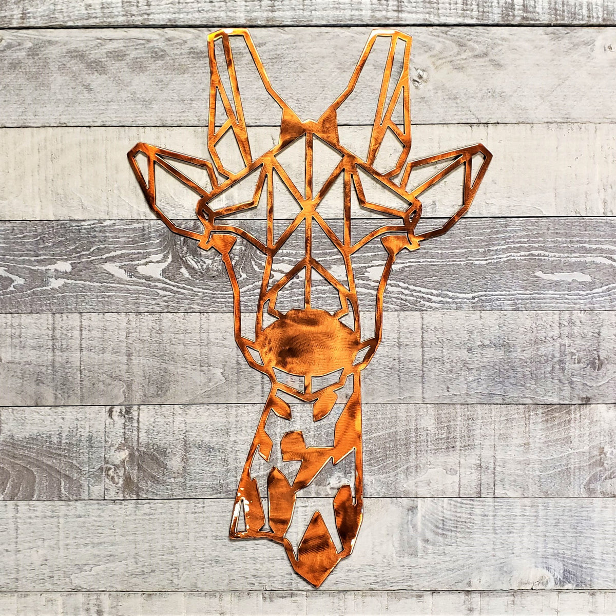 Geometric metal giraffe head wall art on a wooden background