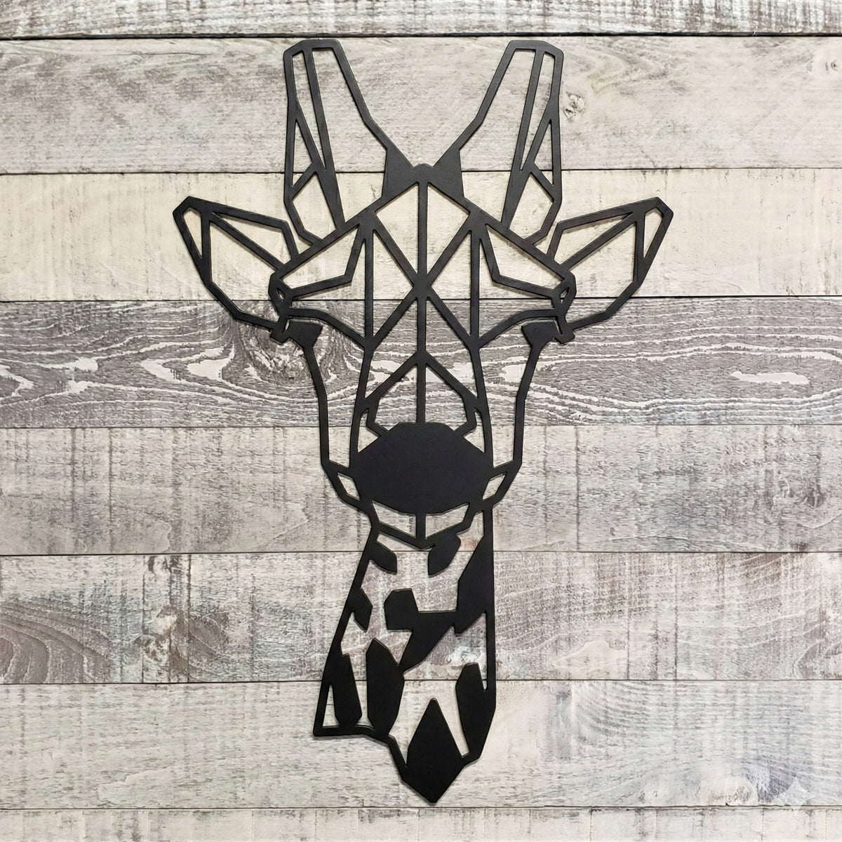 Geometric giraffe metal wall art on a wooden background