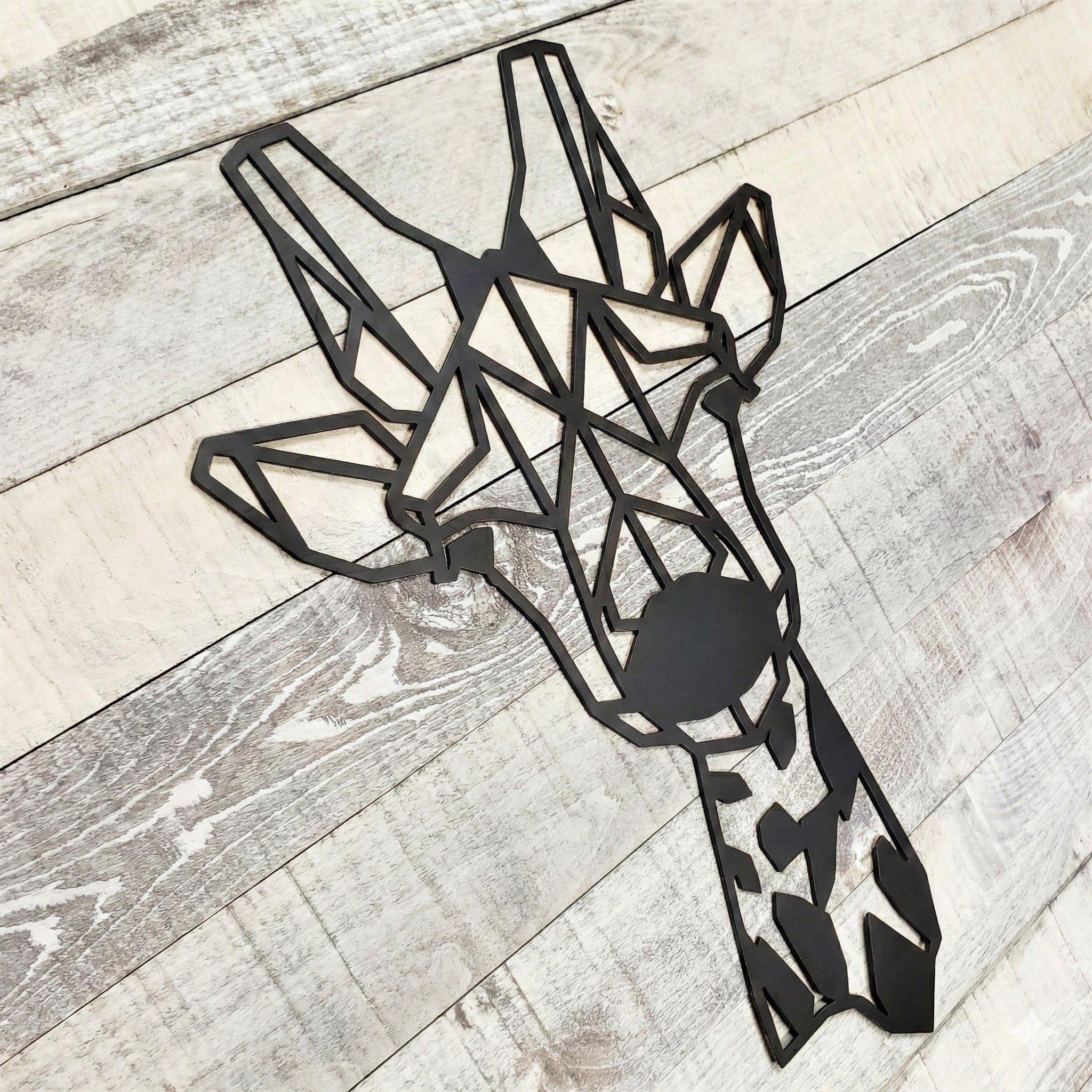 Black geometric giraffe wall art on a wooden floor