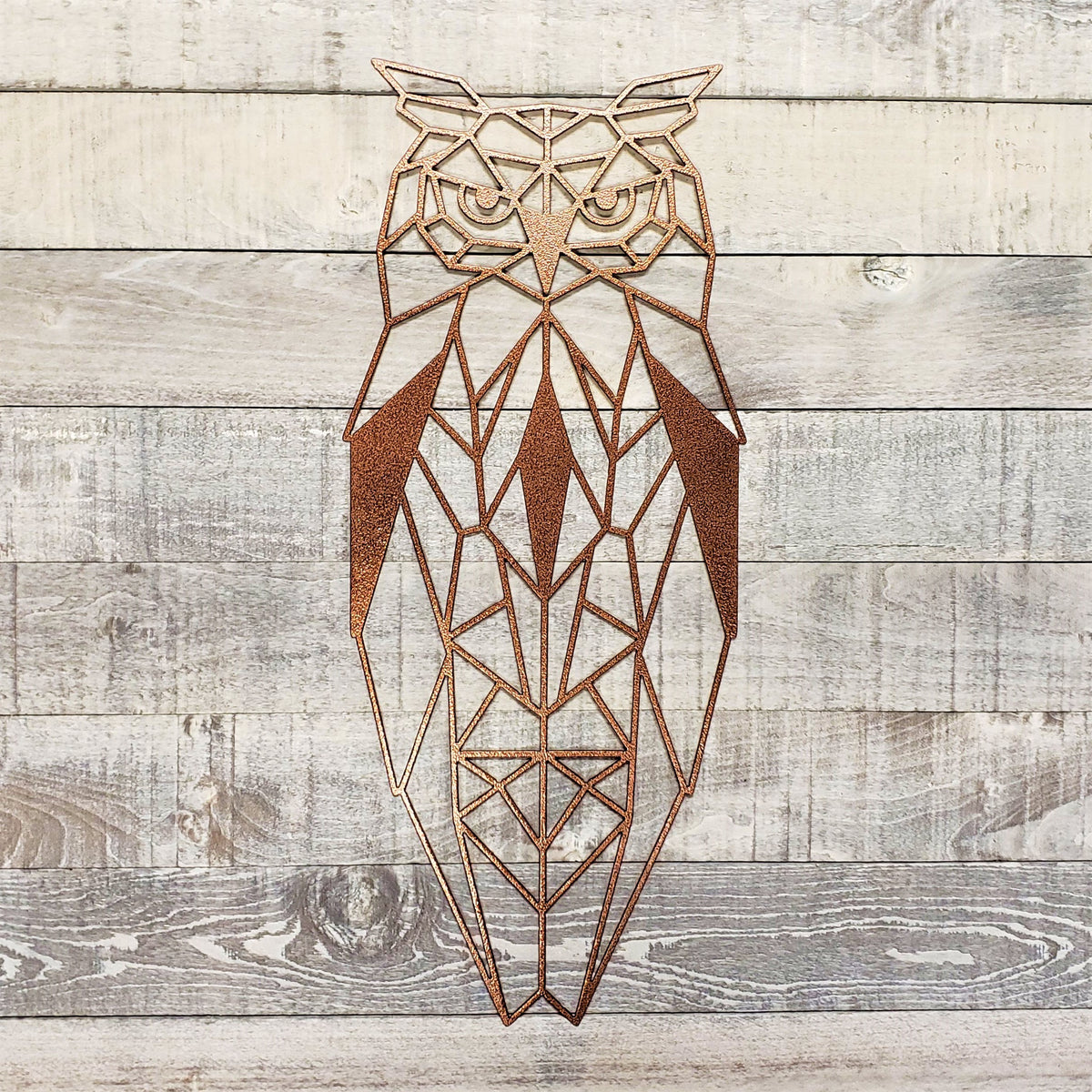 antique copper geometric owl metal wall art on a wooden background