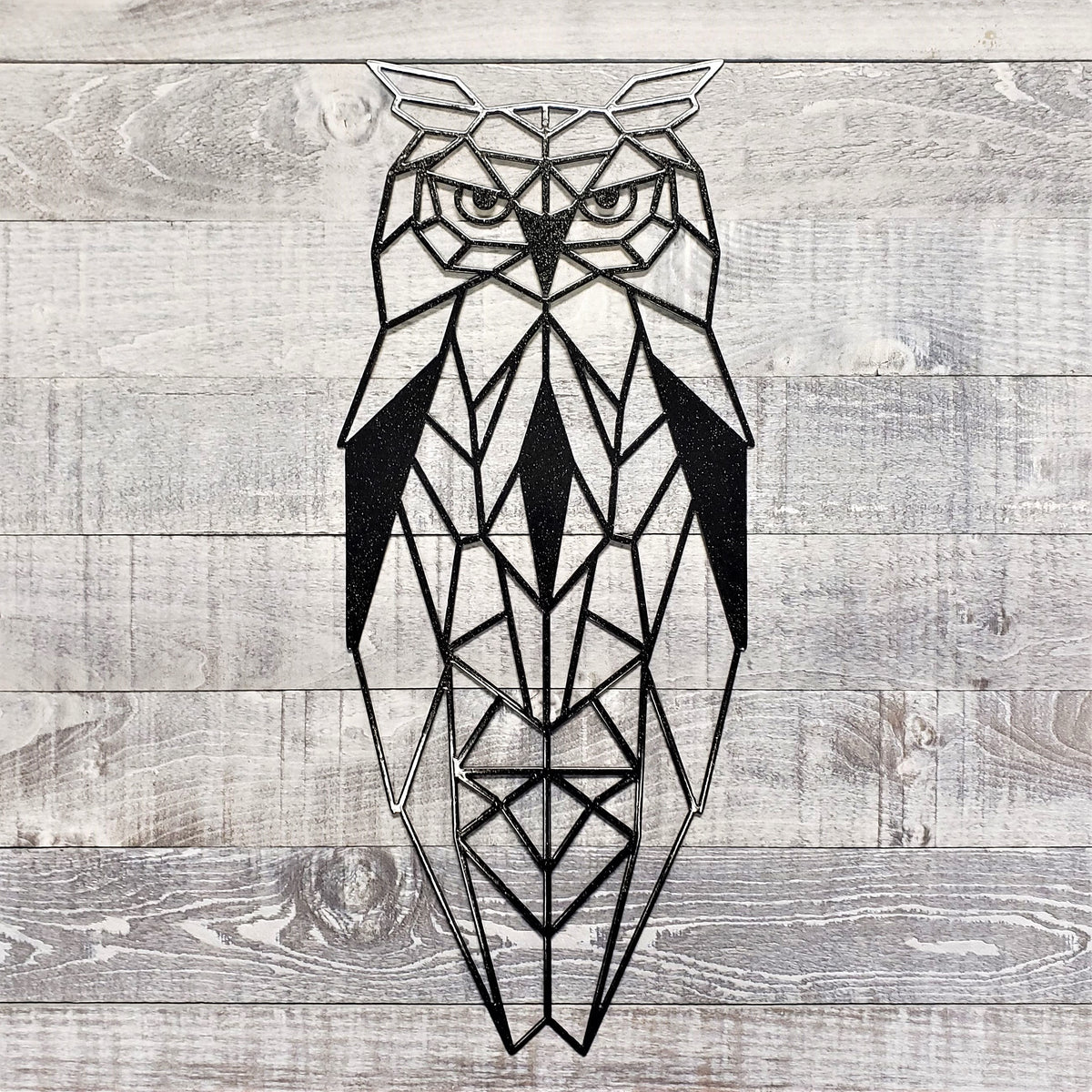 black geometric owl metal wall art on a wooden background