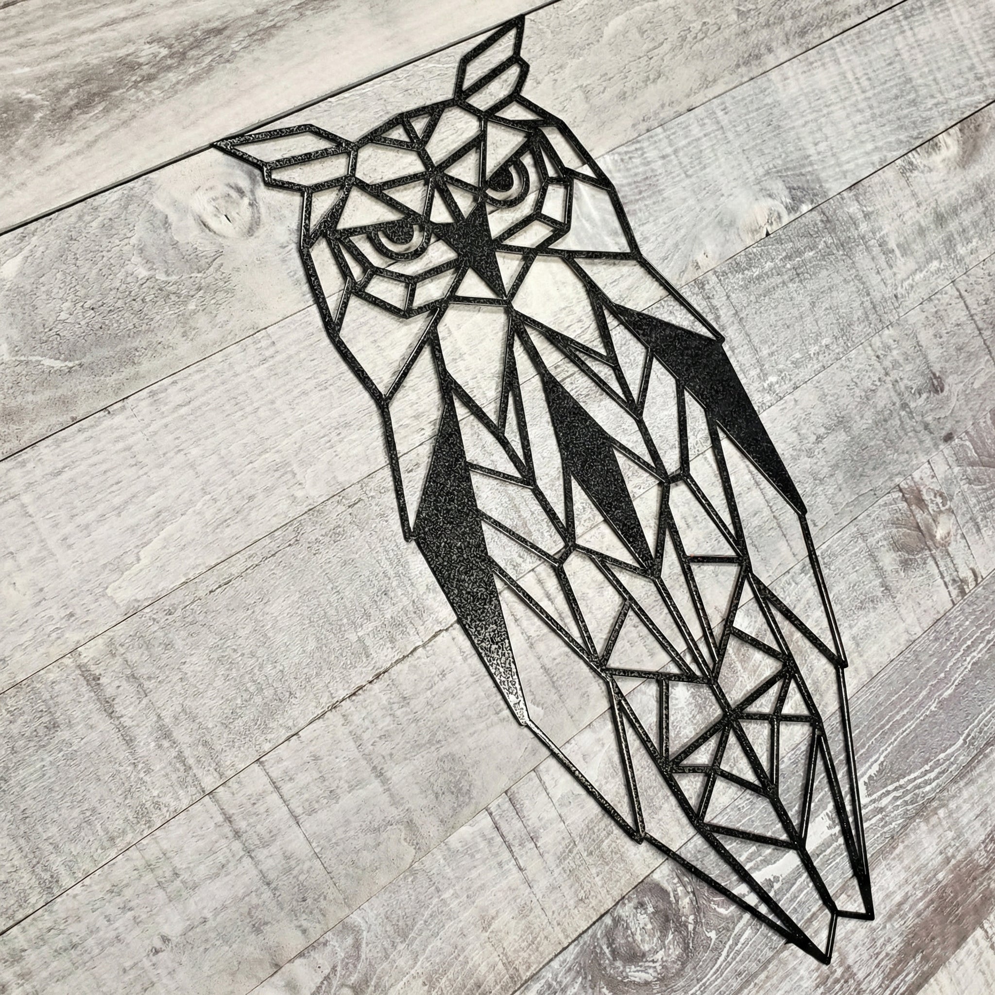 black geometric owl metal wall art on a wooden background