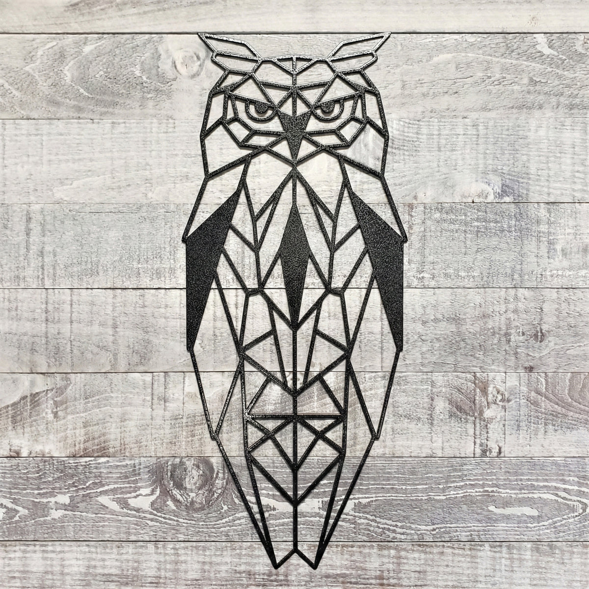 black geometric owl metal wall art on a wooden background