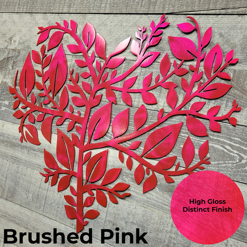 Decorative metal wall art with a 'Brushed Pink' finish on a wooden surface.