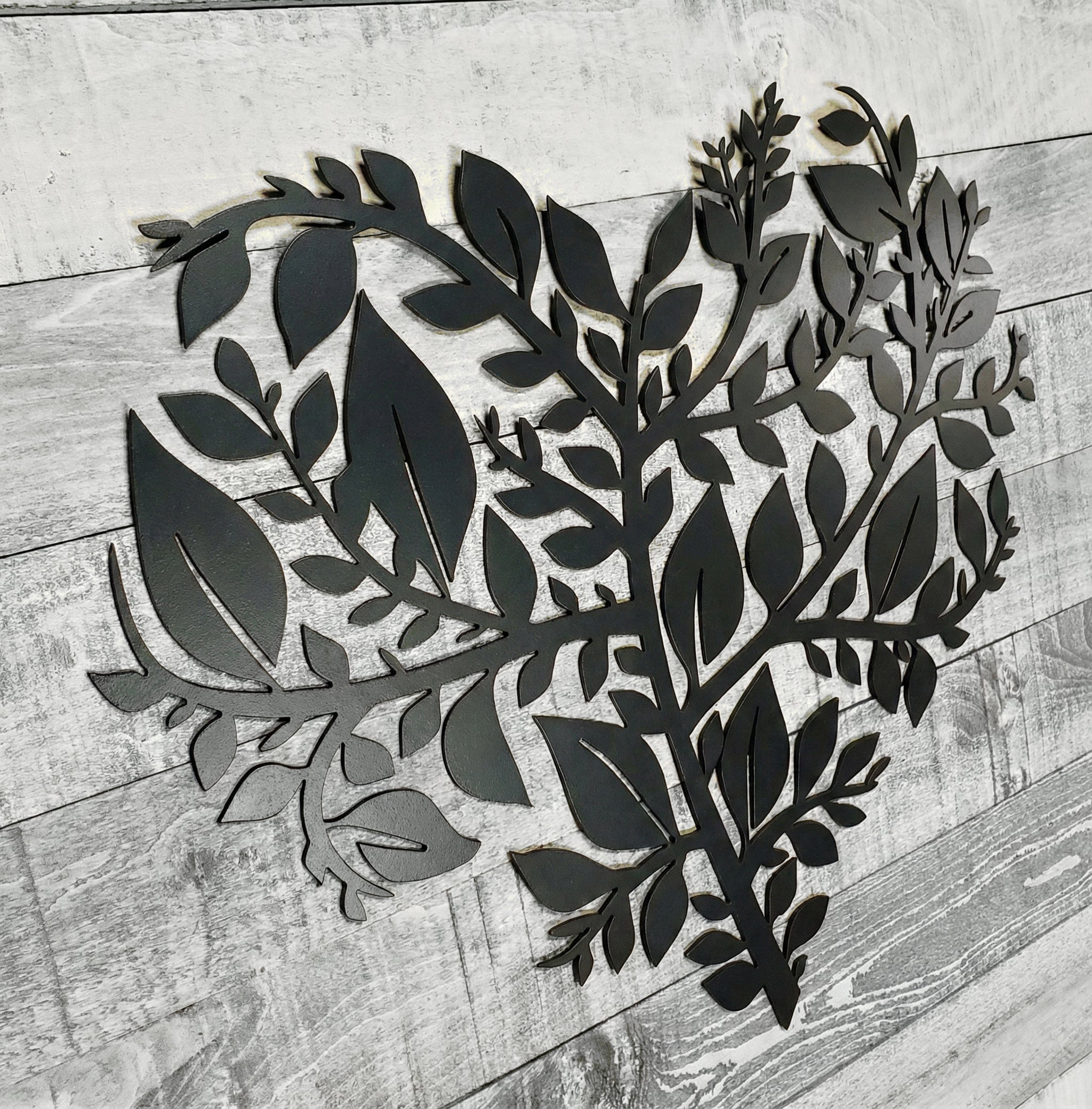 Metal leaves in the shape of a heart on a wooden surface
