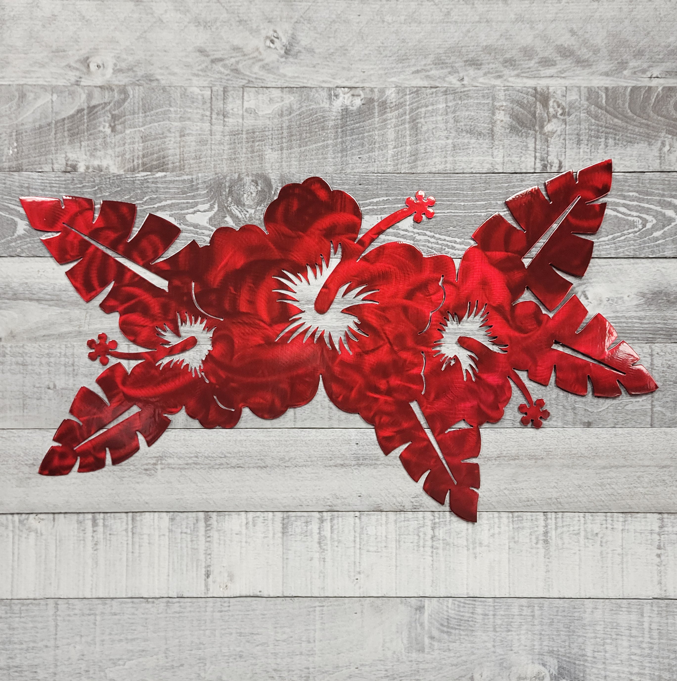 Red floral metal wall art on a wooden background