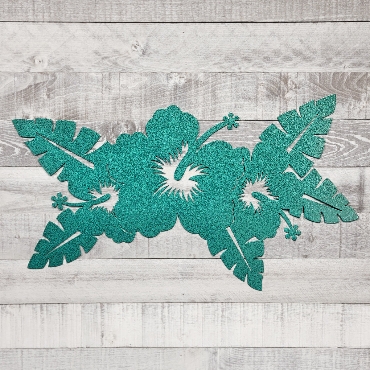 green floral metal wall art on a wooden surface