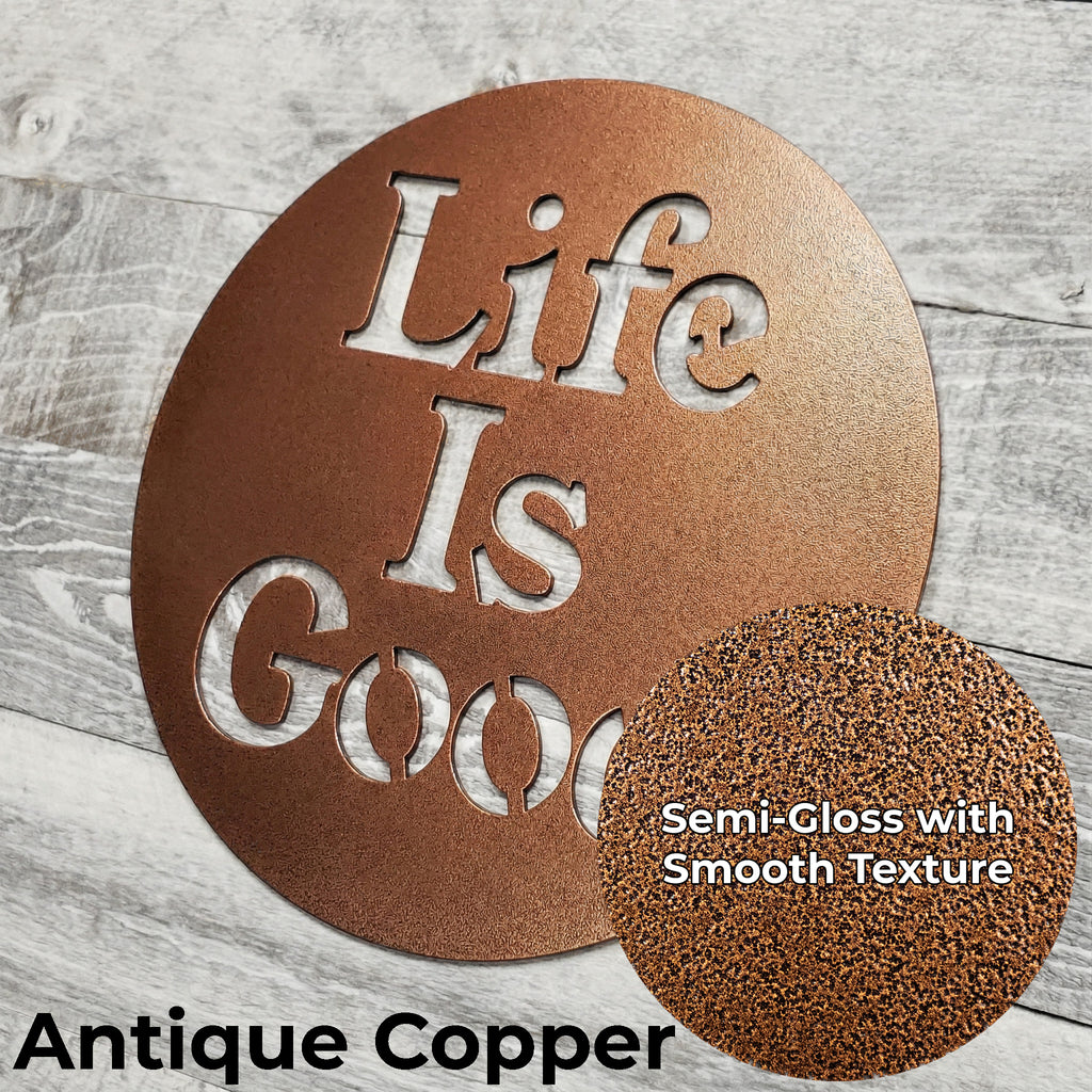 Decorative metal sign with 'Life Is Good' text in antique copper color on a wooden surface.