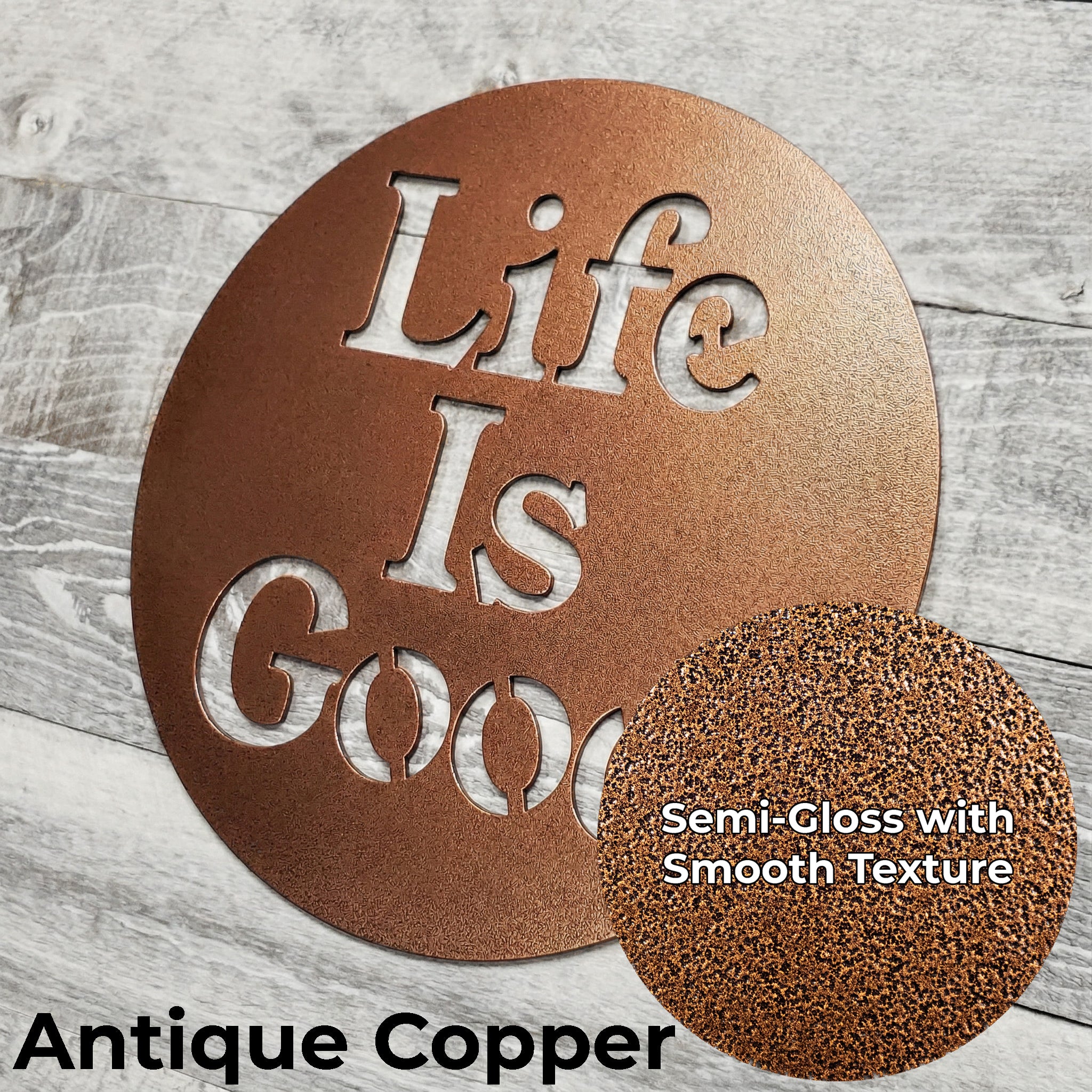 Decorative metal sign with 'Life Is Good' text in antique copper color on a wooden surface.