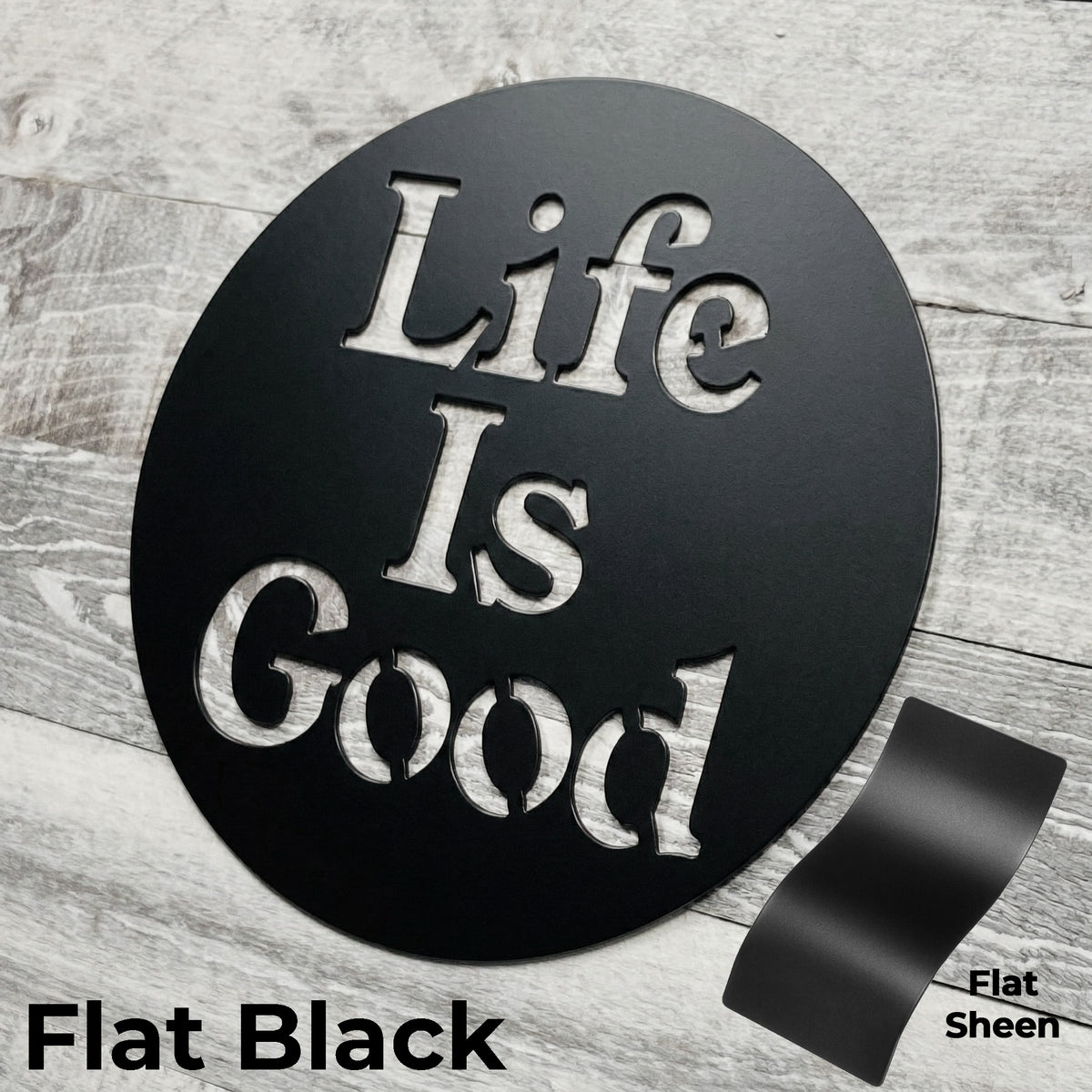 Round black metal sign with 'Life Is Good' text on a wooden surface