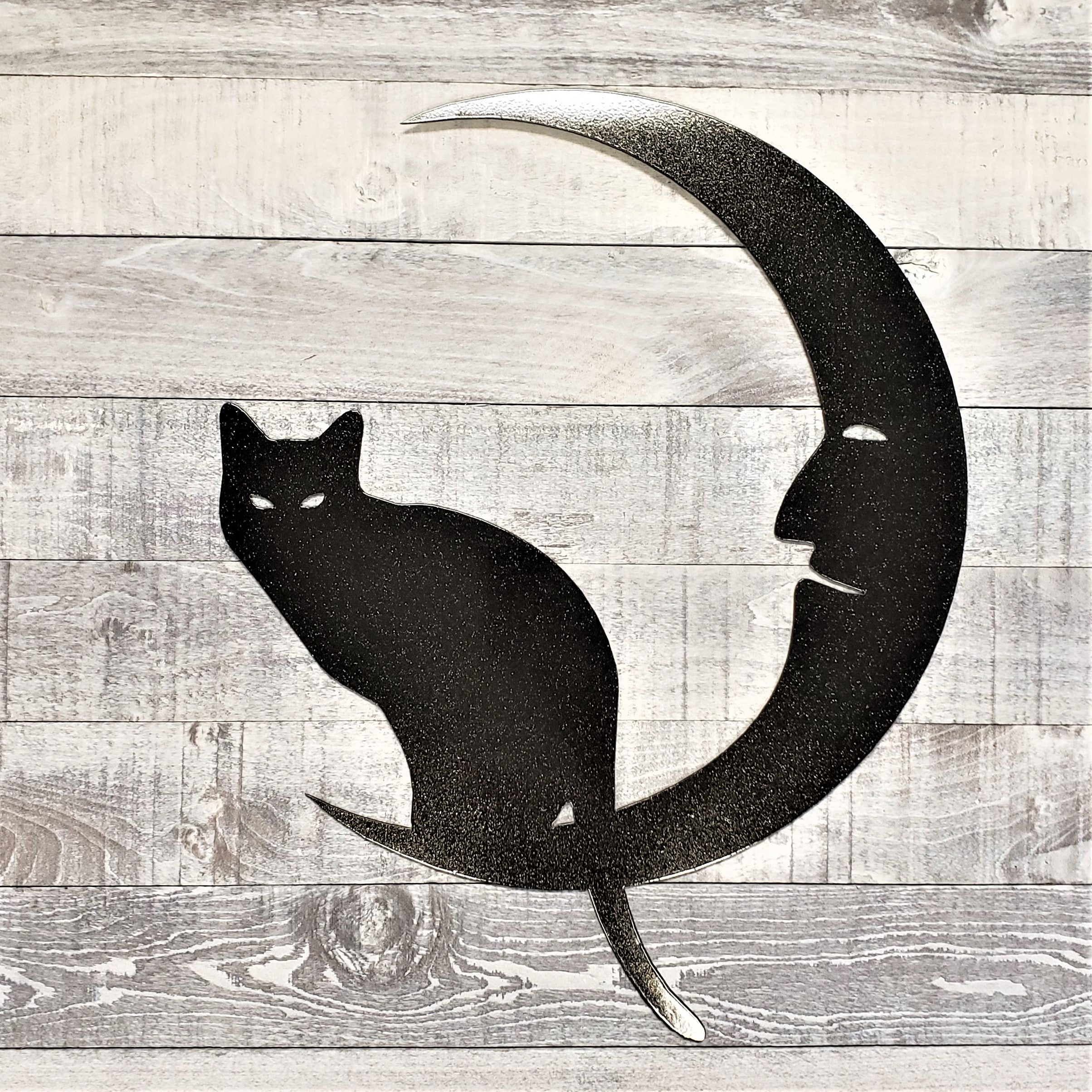 Black silhouette of a cat on a crescent moon against a wooden background