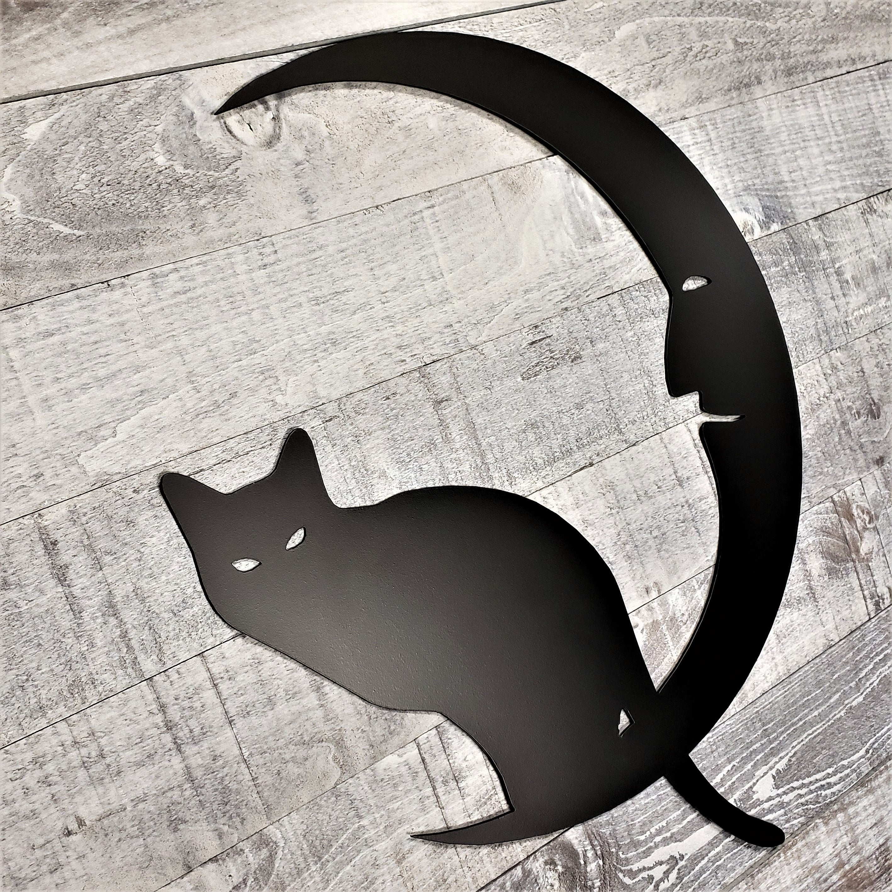 Black cat silhouette on a crescent moon on a wooden background