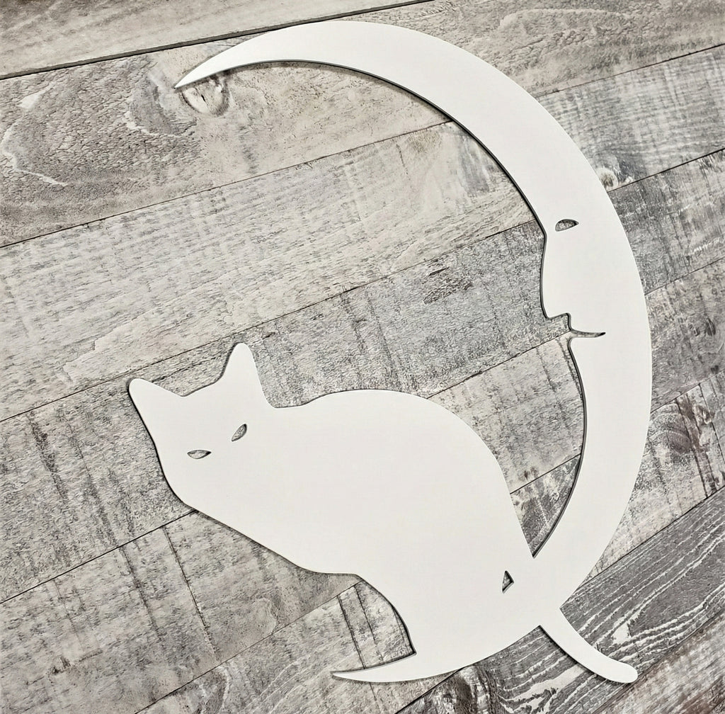 Decorative metal wall art of a cat and crescent moon on a wooden surface