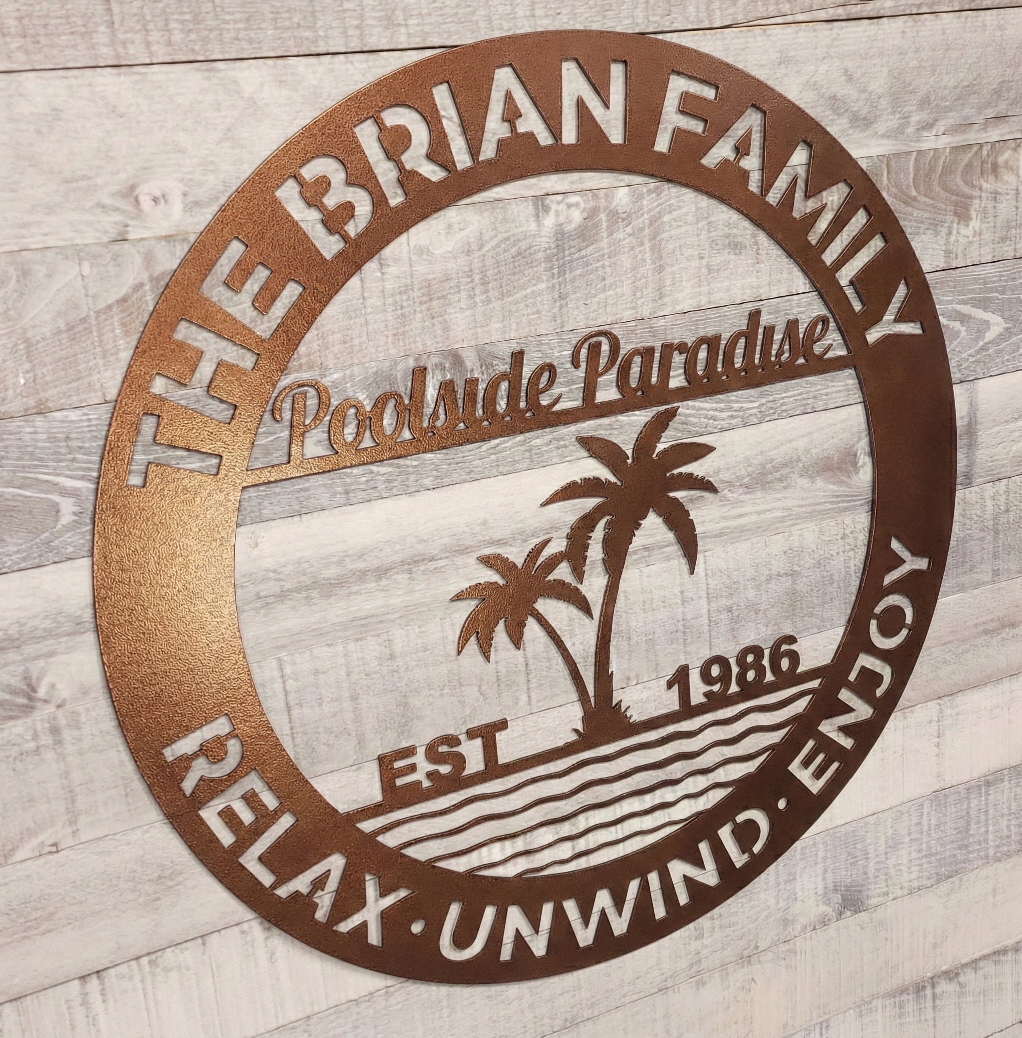 Decorative metal sign for pool patio on a wooden surface.