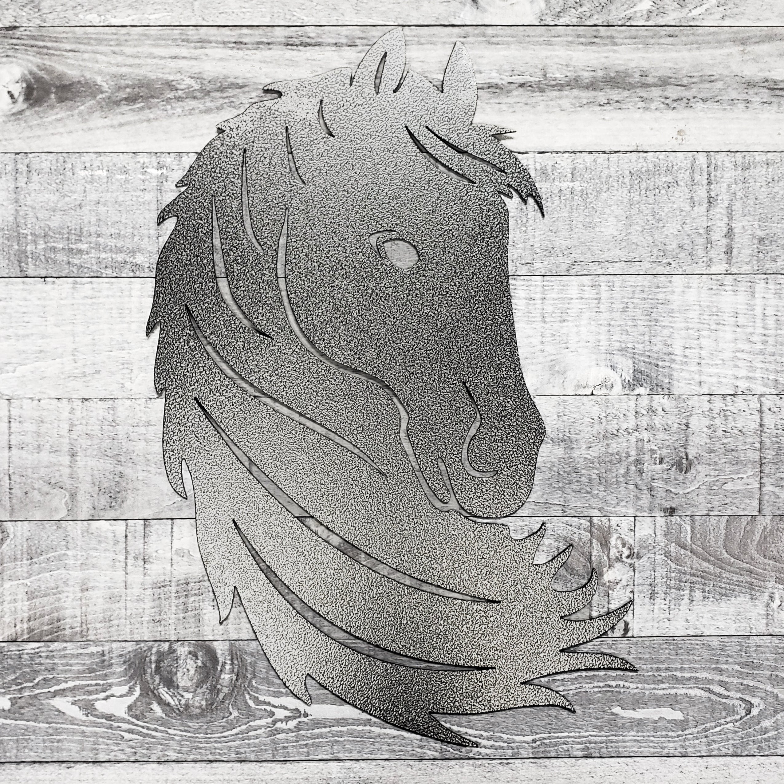 Black and silver metal horse head wall art on a wooden surface