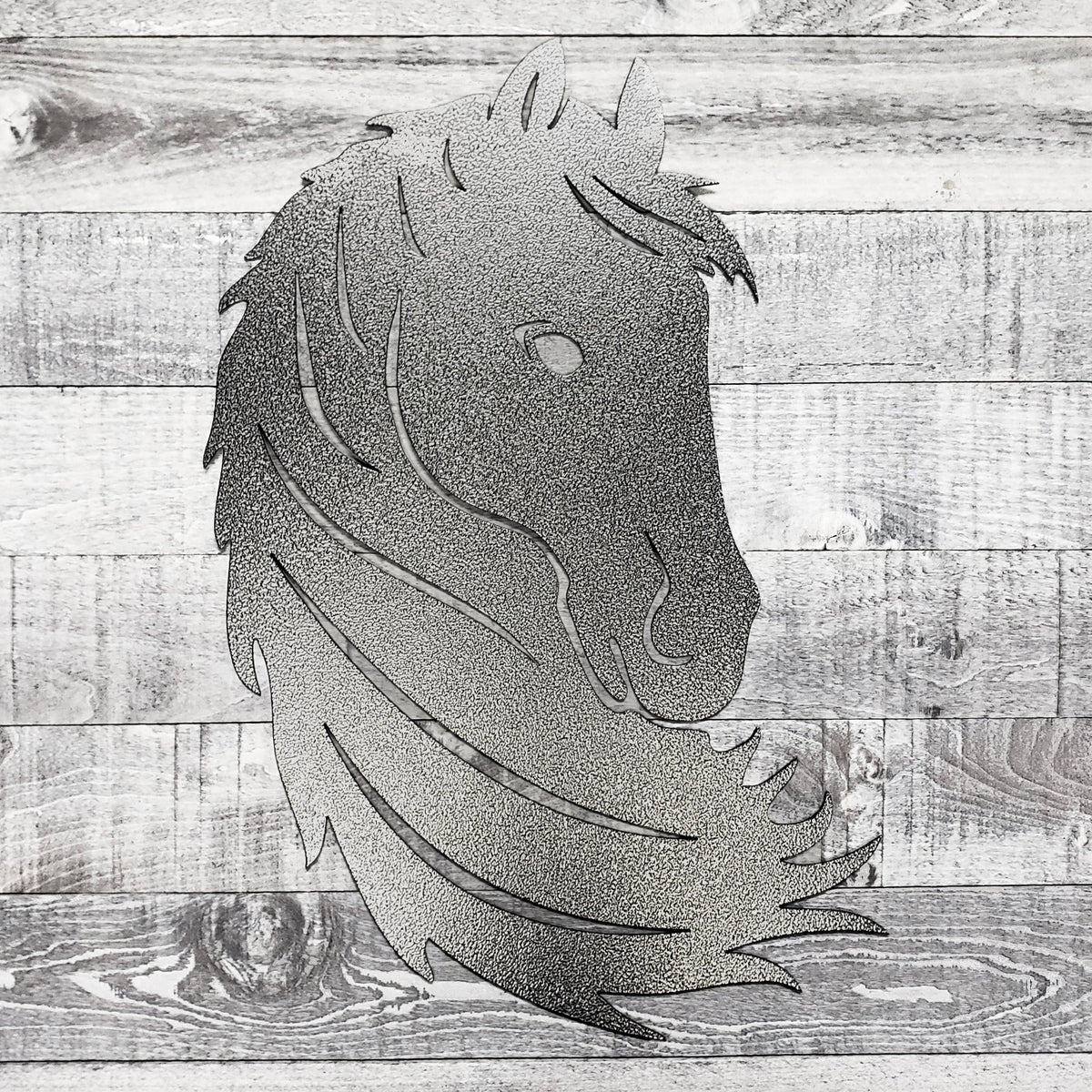 Black and silver metal horse head wall art on a wooden surface