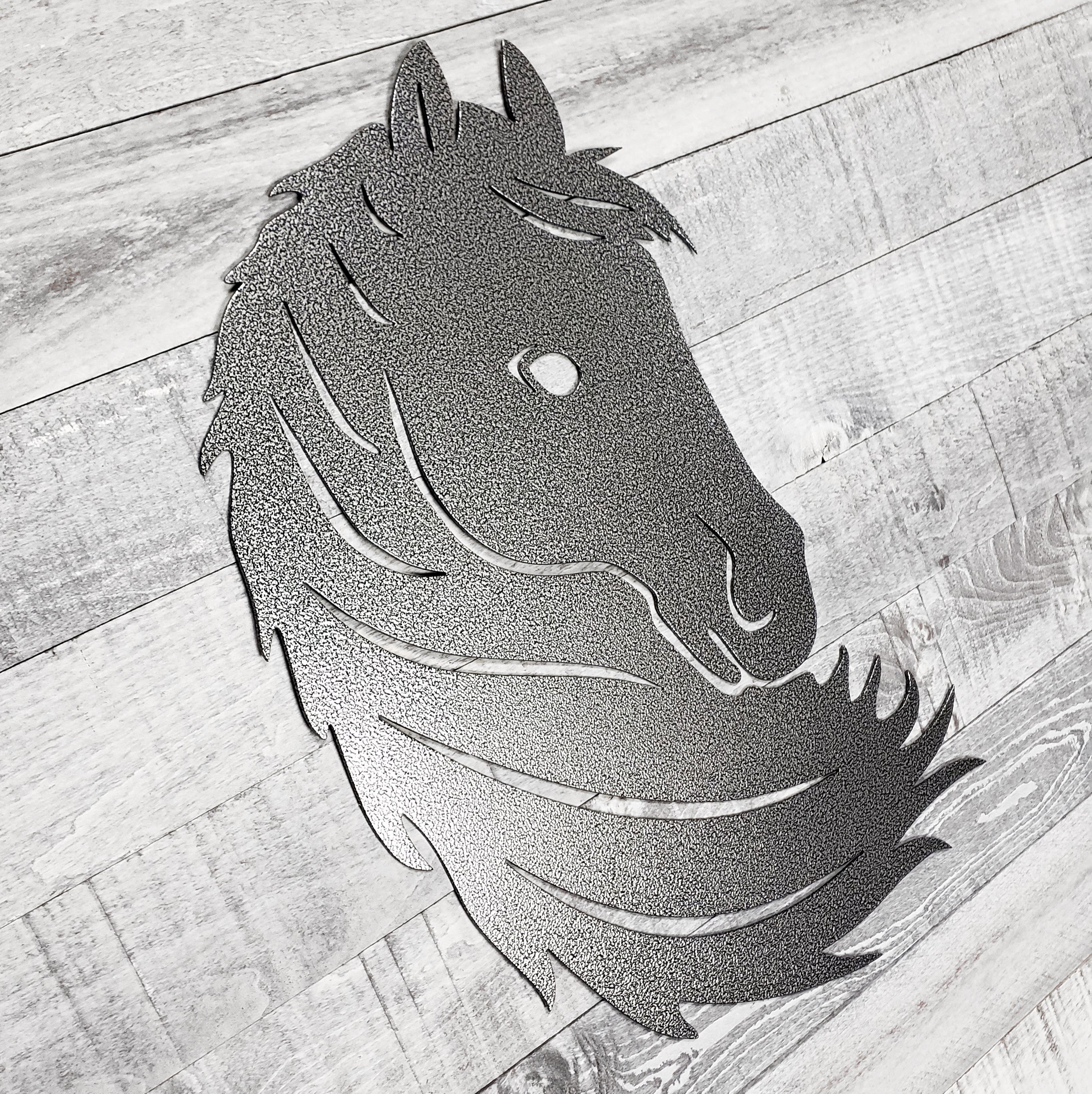 Black and silver metal horse head wall art on a wooden surface