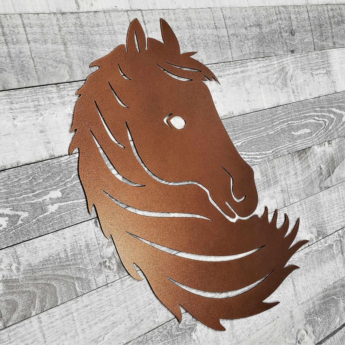 Metallic horse head wall art on a wooden surface