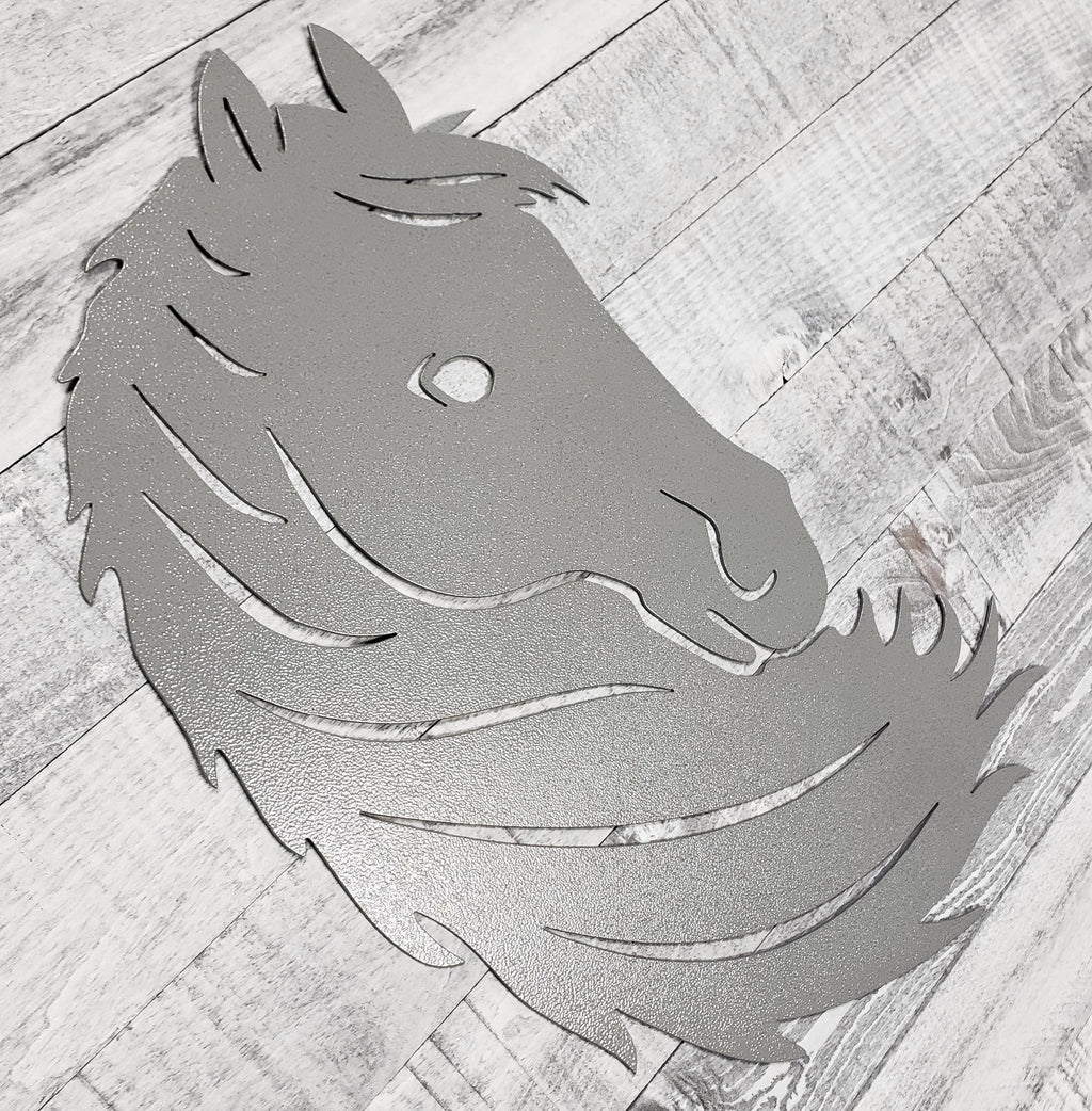 Silver metal horse head wall art on a wooden surface