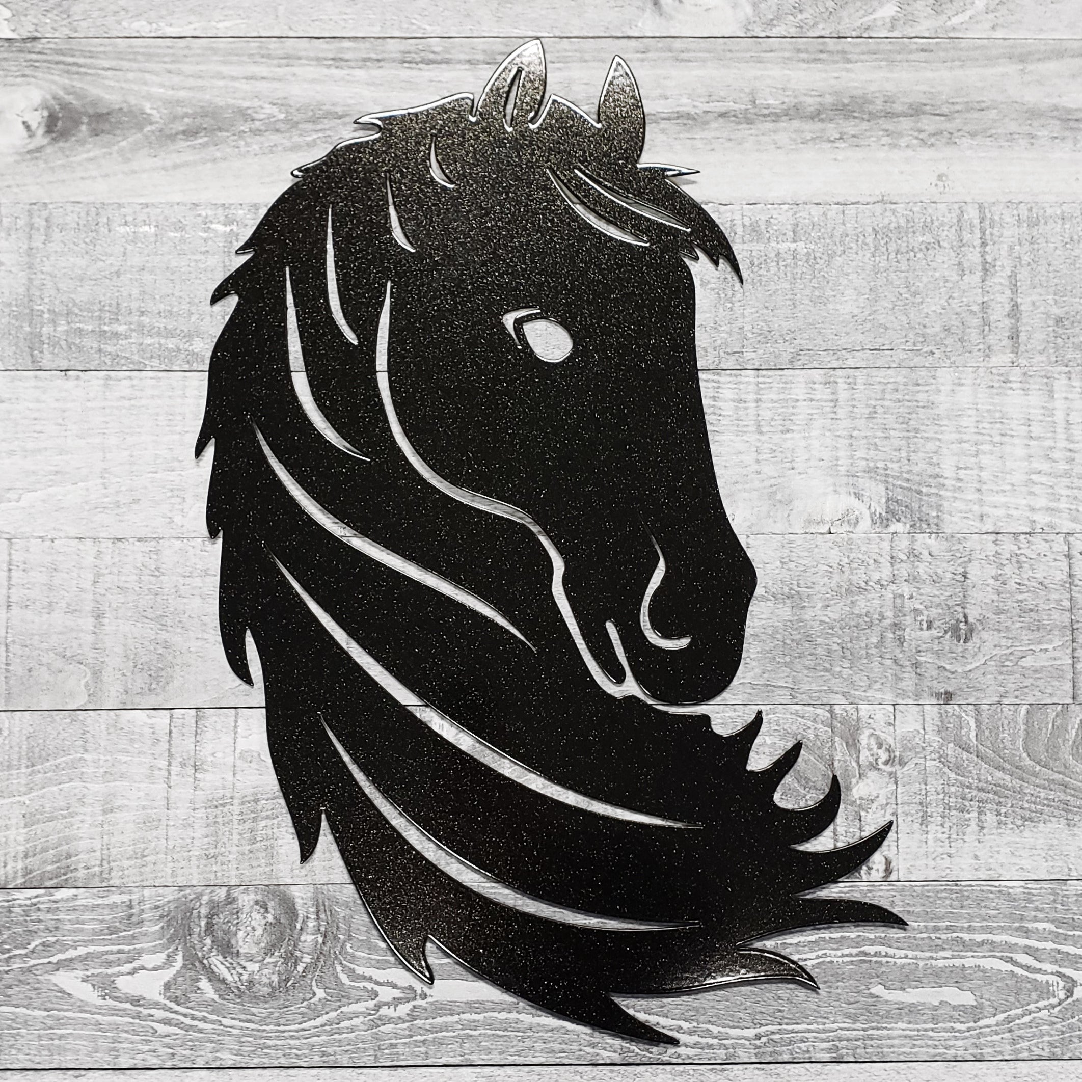 Black metal horse head wall art on a wooden surface