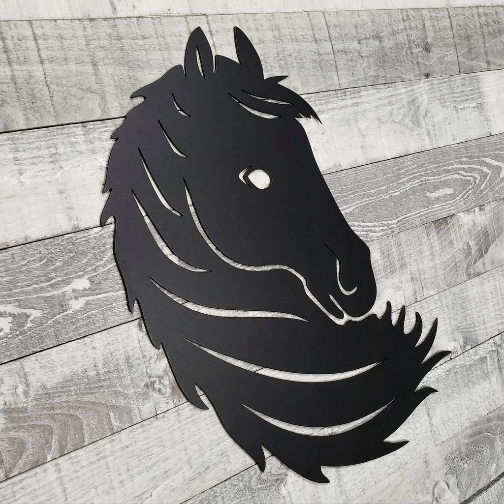 Black metal horse head wall art on a wooden surface
