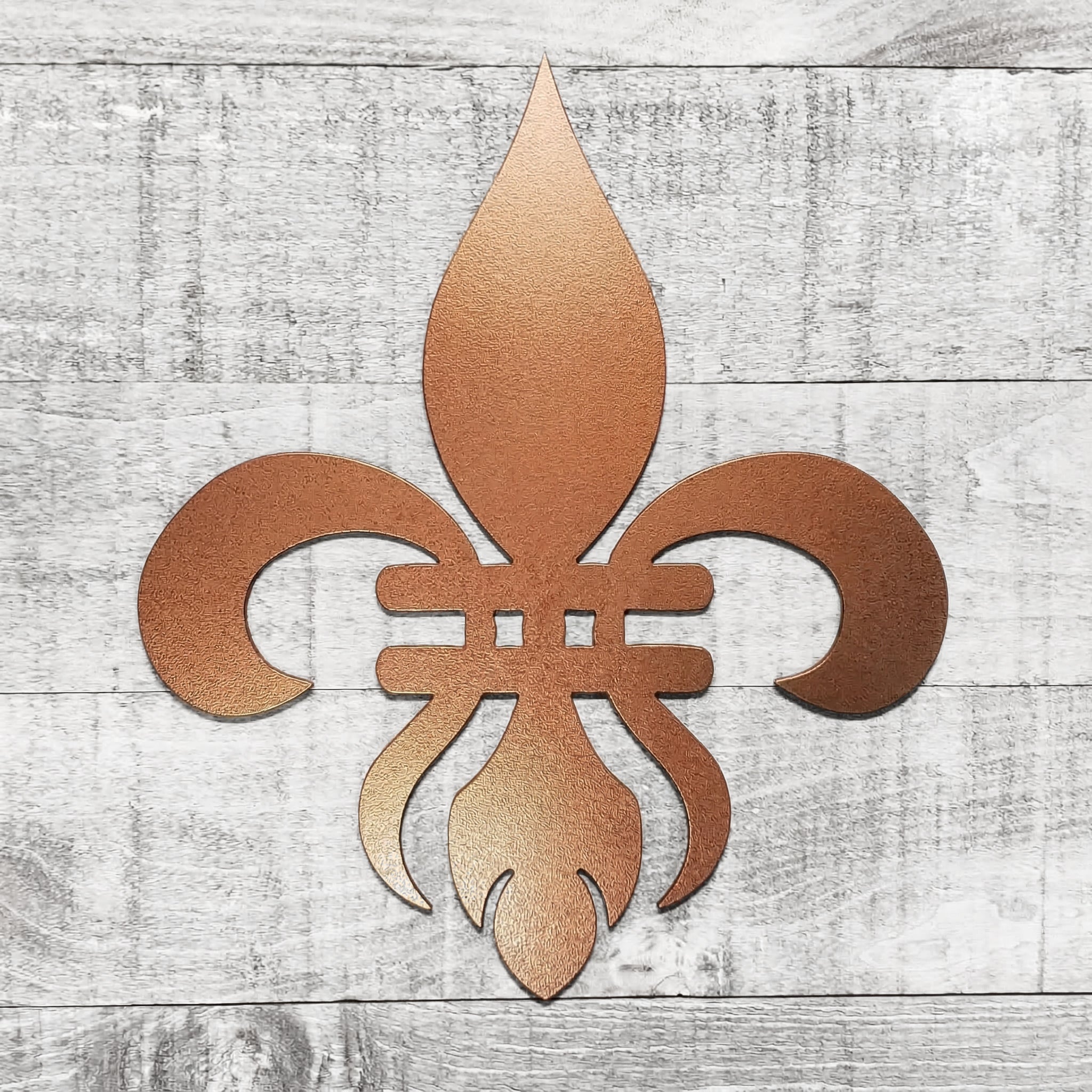Decorative copper-colored metal fleur-de-lis on a wooden background