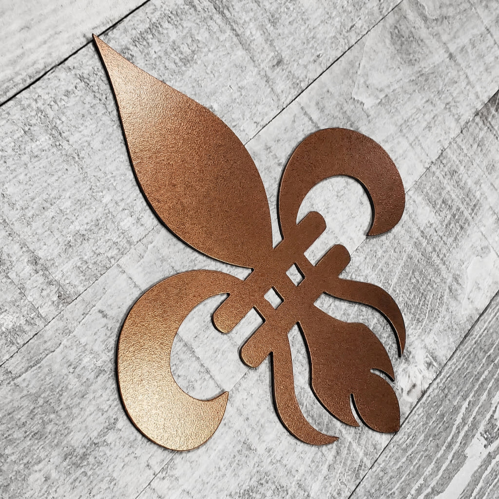 Decorative copper-colored metal fleur-de-lis on a wooden background