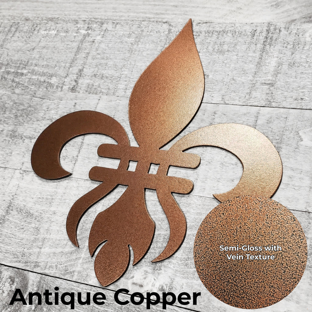 Decorative copper-colored metal fleur-de-lis on a wooden background with a close-up of the color finish