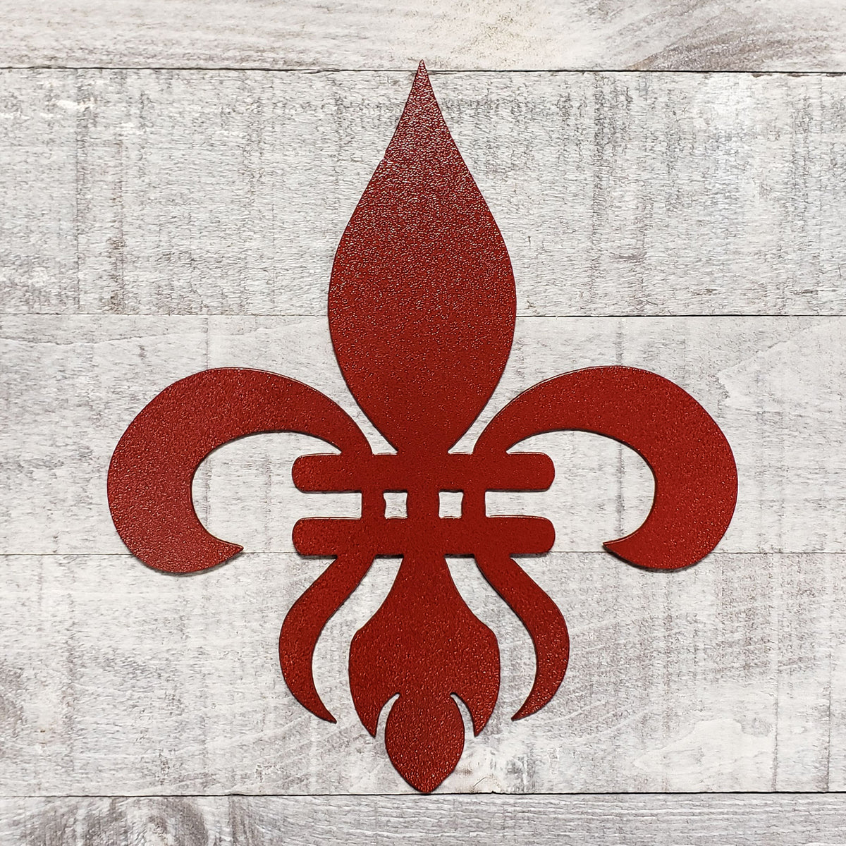 Decorative red metal fleur-de-lis on a wooden background