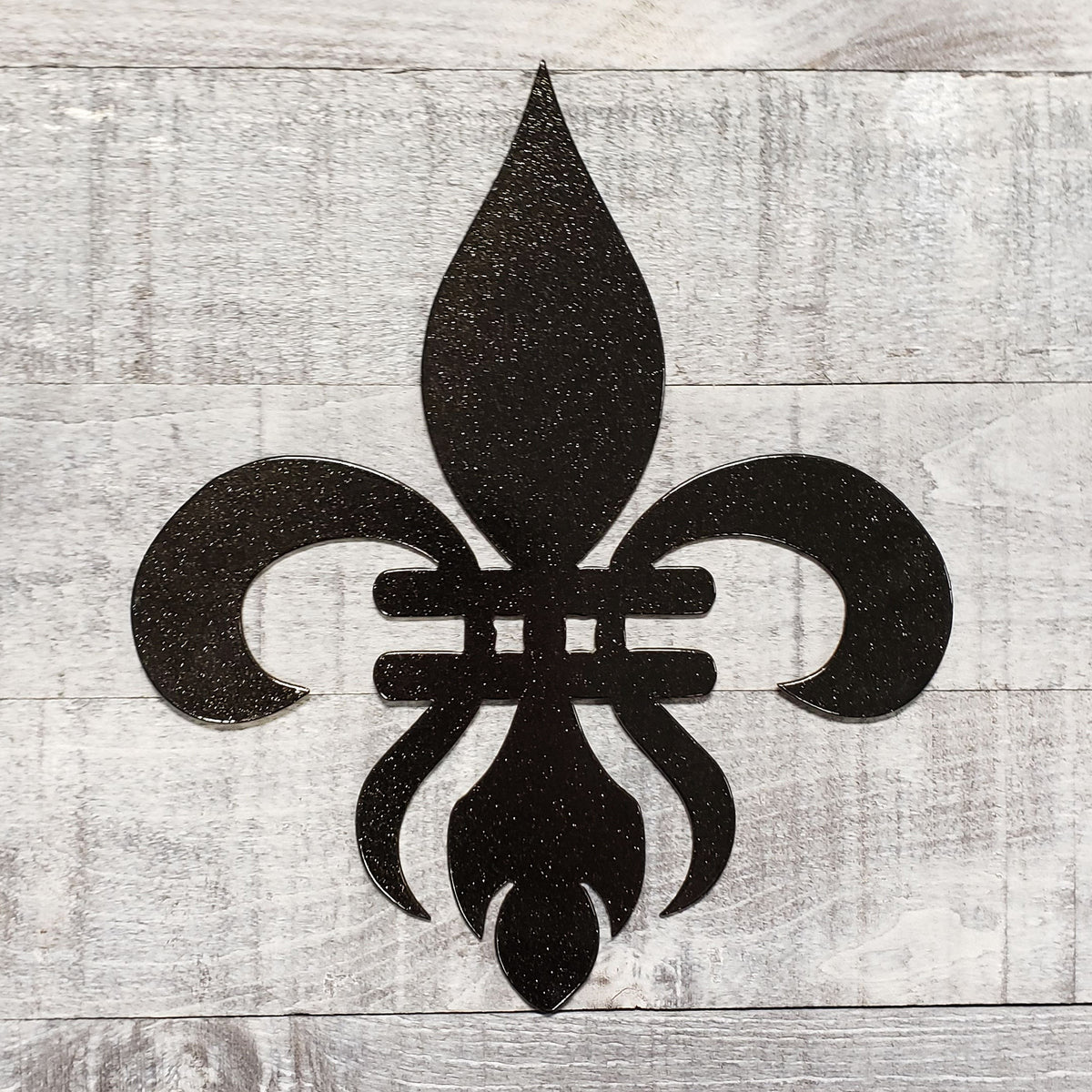 Decorative black metal fleur-de-lis on a wooden background