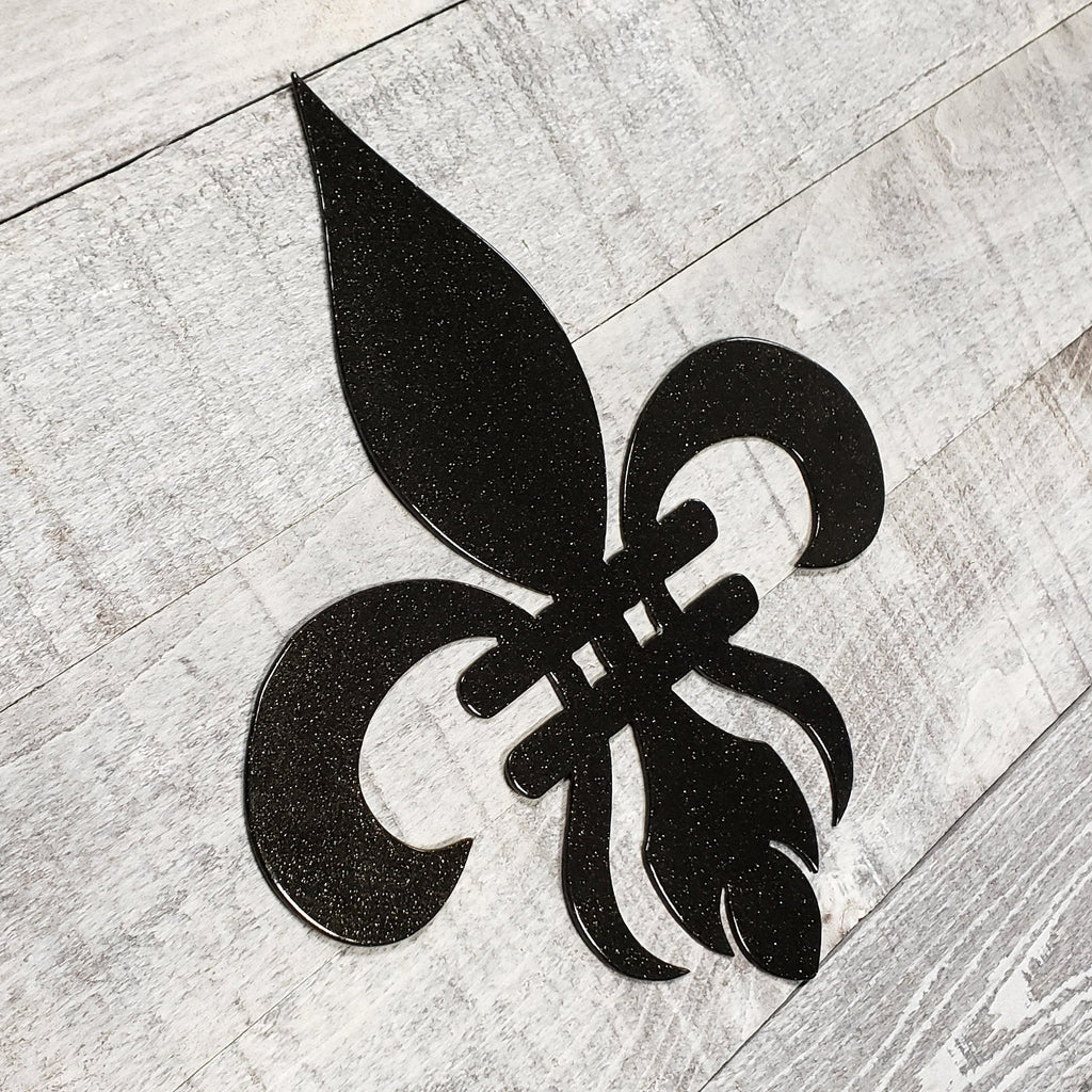 Decorative black metal fleur-de-lis on a wooden background